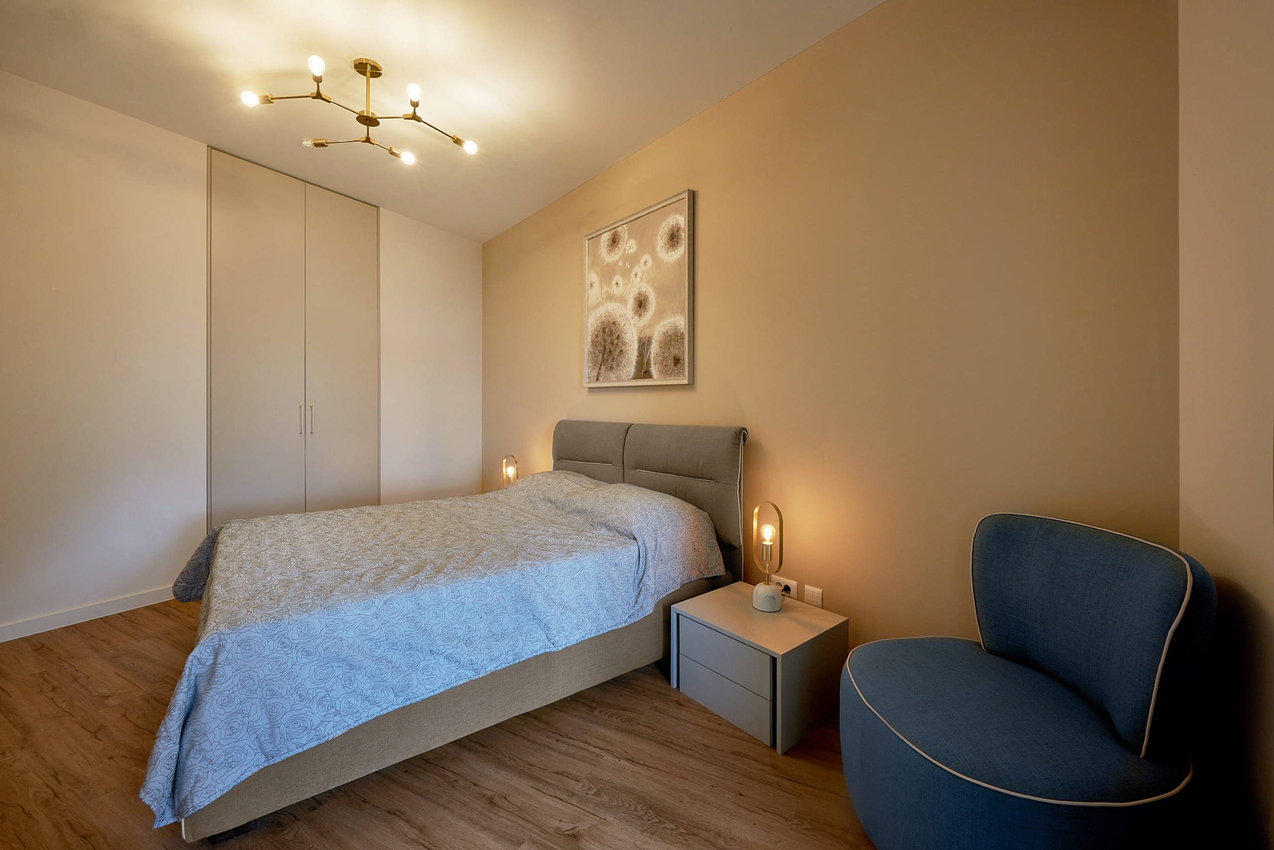Chambre moderne dans un appartement à Bečići, Monténégro : lit double, placard intégré et fauteuil bleu.