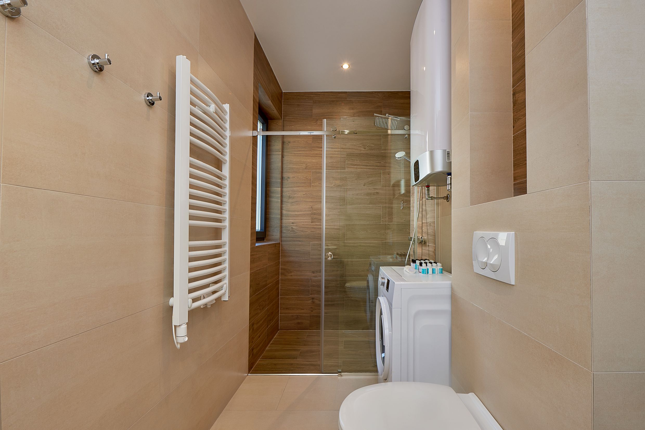 Salle de bain moderne avec douche et machine à laver dans un appartement, Bečići, Monténégro.