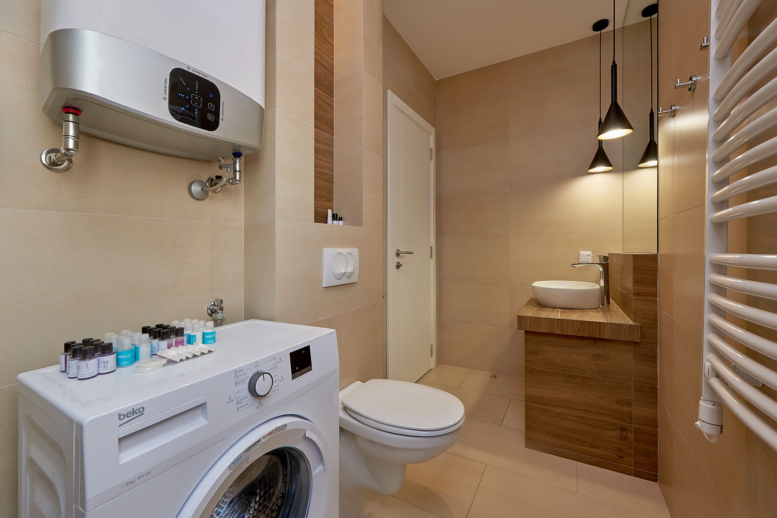 Salle de bain moderne avec douche et machine à laver dans un appartement à Bečići, Monténégro.