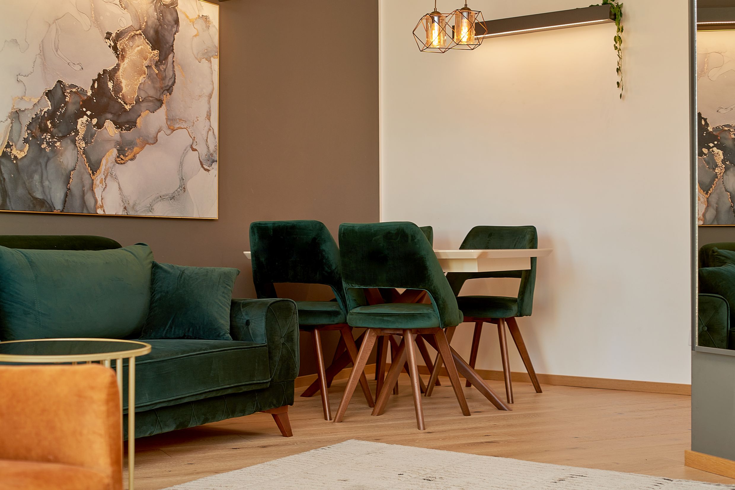 Salon moderne avec des fauteuils en velours émeraude et un coin repas dans un appartement à Bečići, Monténégro.