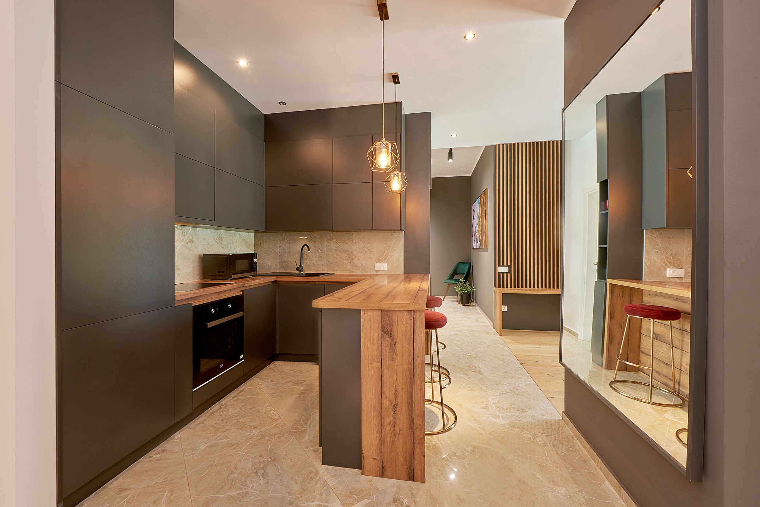 Cuisine moderne dans un appartement à Bečići, Monténégro : façades sombres, comptoir bar, sol en marbre et décoration élégante.