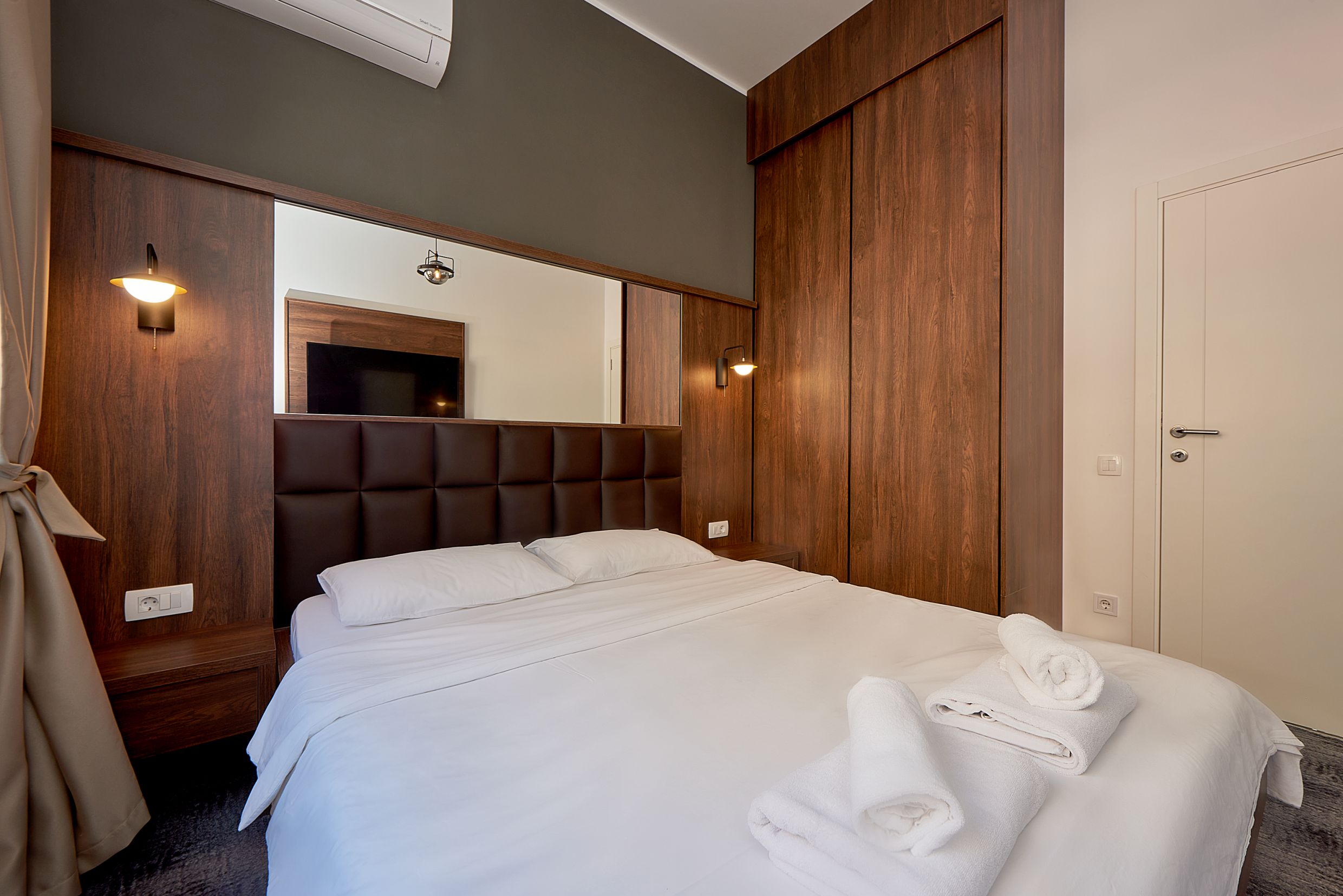 Chambre moderne avec lit double et armoire en bois dans un appartement à Bečići, Monténégro.