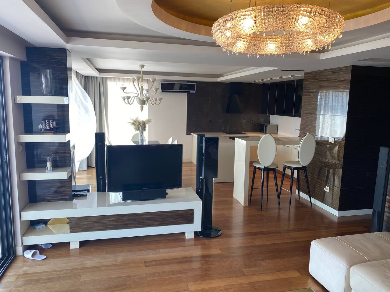 Salon z designerskim żyrandolem, meblami i kuchnią w luksusowym apartamencie w Budvie, Czarnogóra