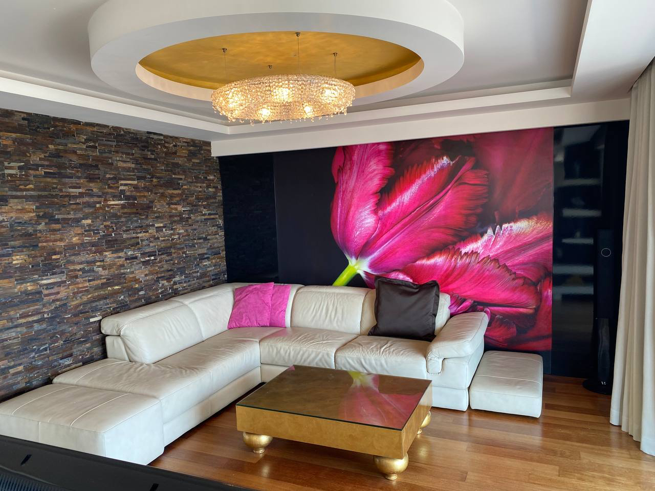 Przestronny salon w apartamencie w Budvie, Czarnogóra: białe skórzane meble tapicerowane, ściana akcentowa z fotodrukiem tulipana, o...