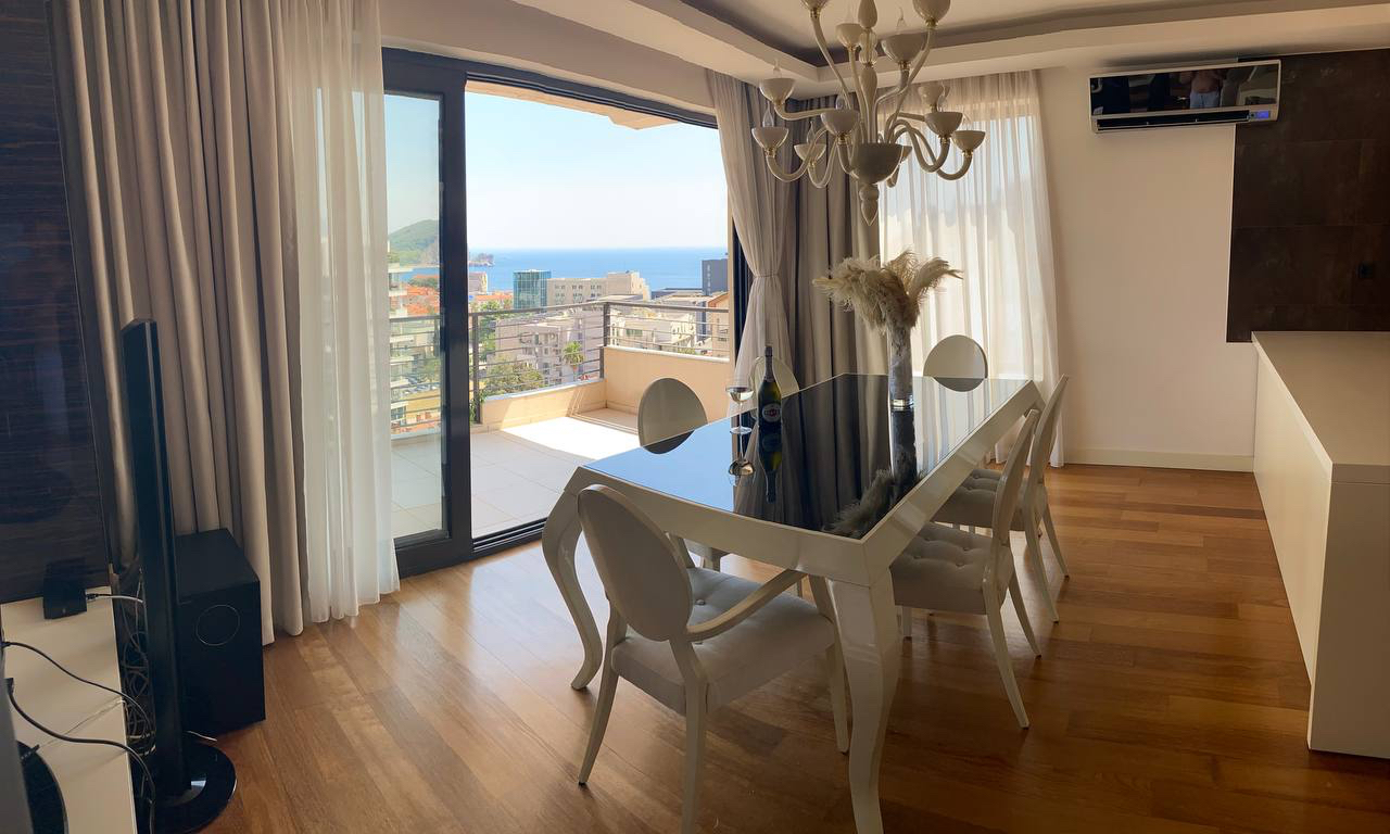Przestronny salon z jadalnią, panoramicznymi oknami i widokiem na morze w apartamencie w Budvie, Czarnogóra