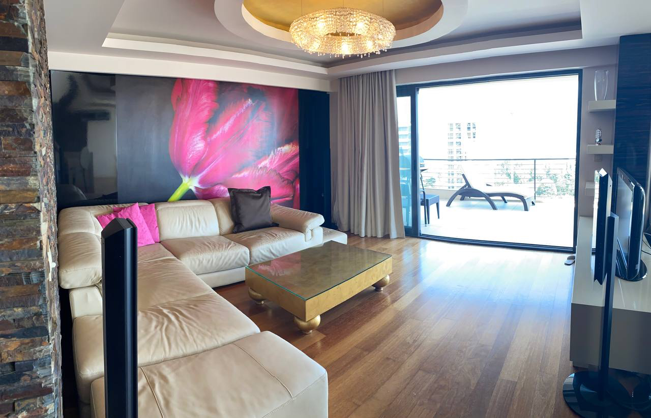 Przestronny salon z białym skórzanym narożnikiem i panoramicznym oknem w apartamencie w Budvie, Czarnogóra