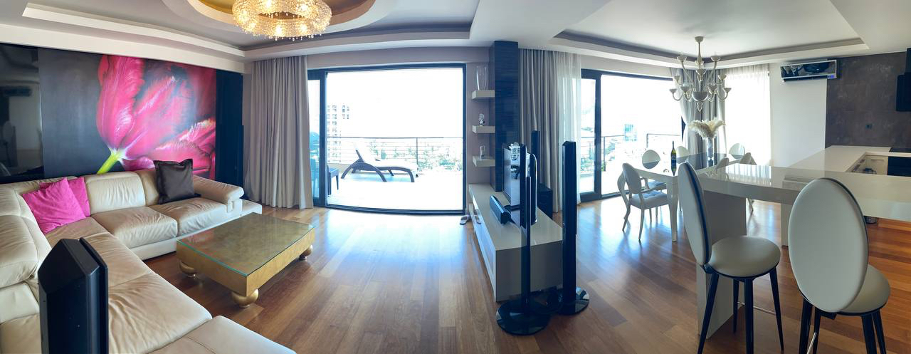 Przestronny salon z białym narożnikiem, panoramicznymi oknami i tarasem w ekskluzywnym apartamencie w Budvie, Czarnogóra