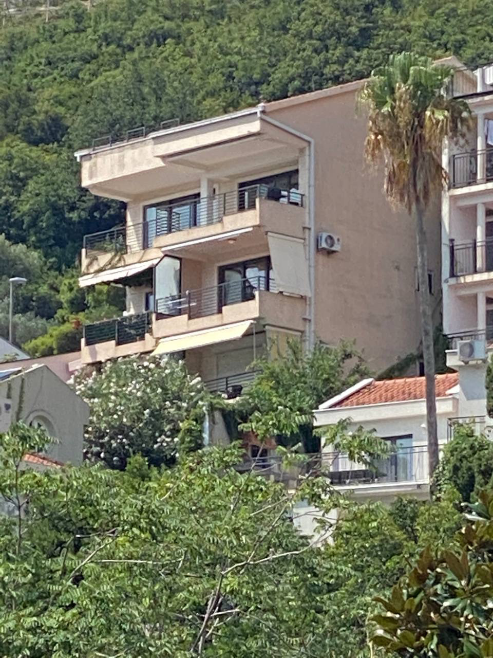Nowoczesny budynek mieszkalny z balkonami i panoramicznym widokiem na zielone góry w Budvie, Czarnogóra