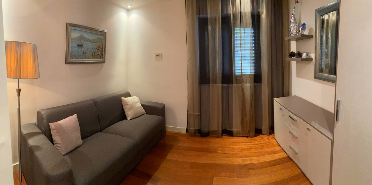 Przytulny salon z szarą sofą, komodą i parkietem w apartamencie w Budvie, Czarnogóra