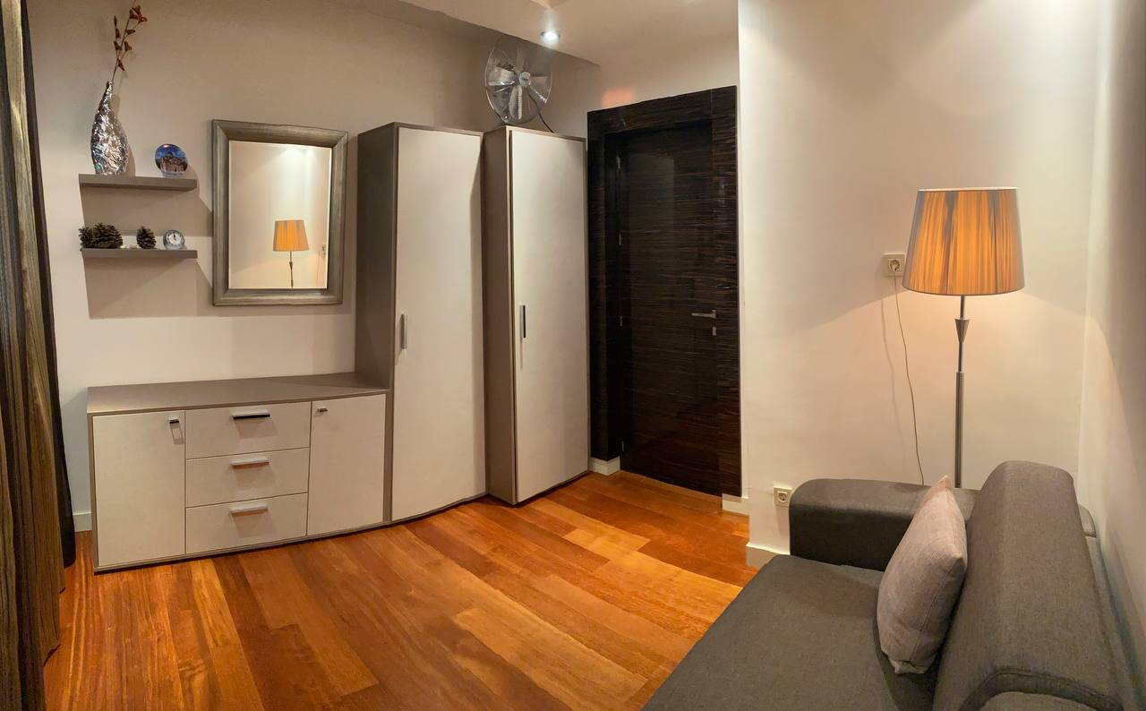 Nowoczesny salon z parkietem, jasnymi meblami, szafą i sofą w mieszkaniu w Budvie, Czarnogóra
