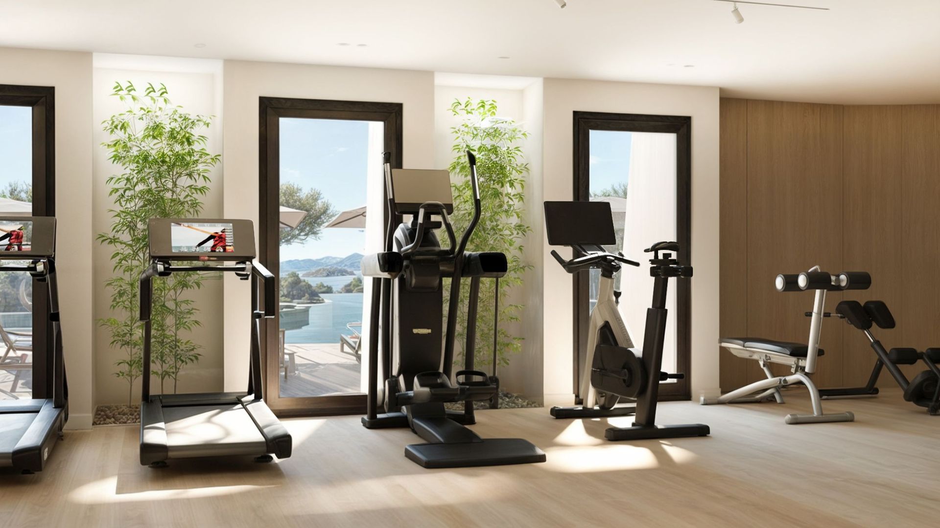 Salle de sport moderne dans le ЖК Reževići, Monténégro : tapis de course, elliptique et vue sur la mer à travers de grandes baies vitrées.
