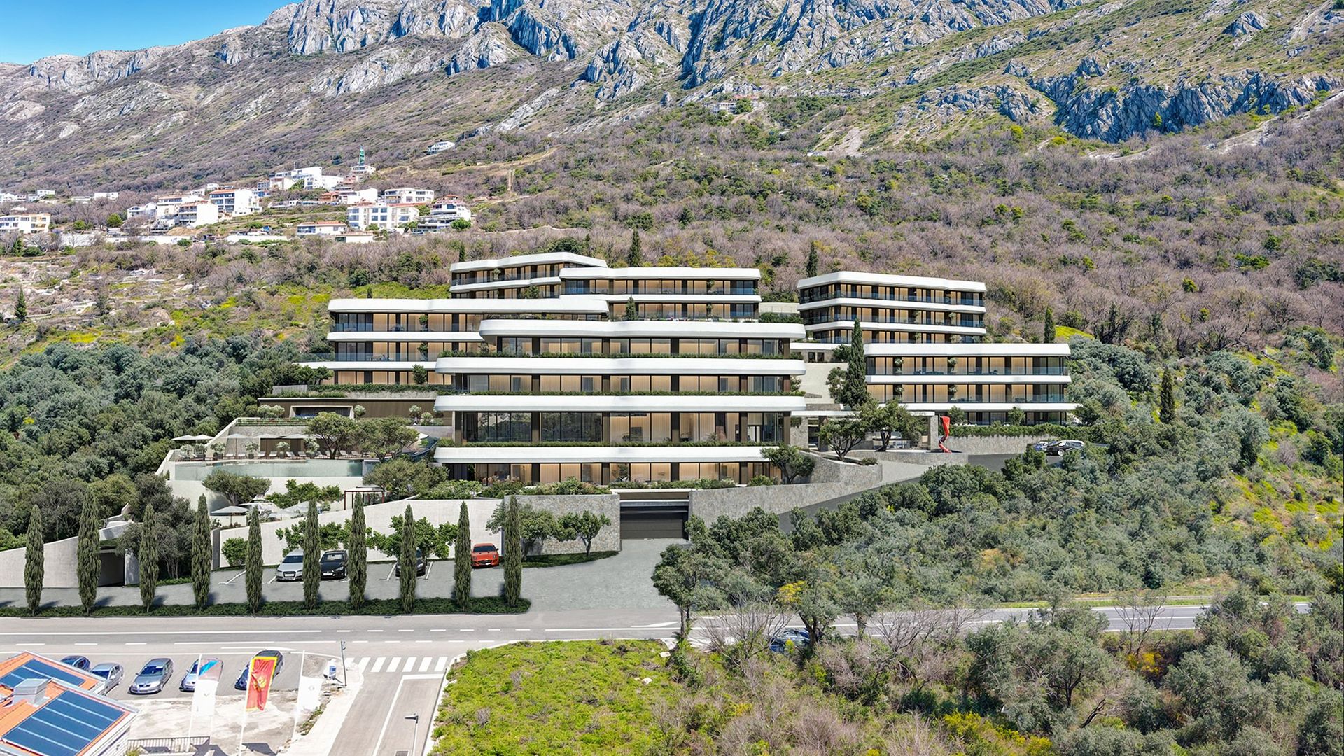 Complexe résidentiel moderne à Reževići, Monténégro : vue panoramique sur des bâtiments en cascade avec terrasses au pied des montagnes.