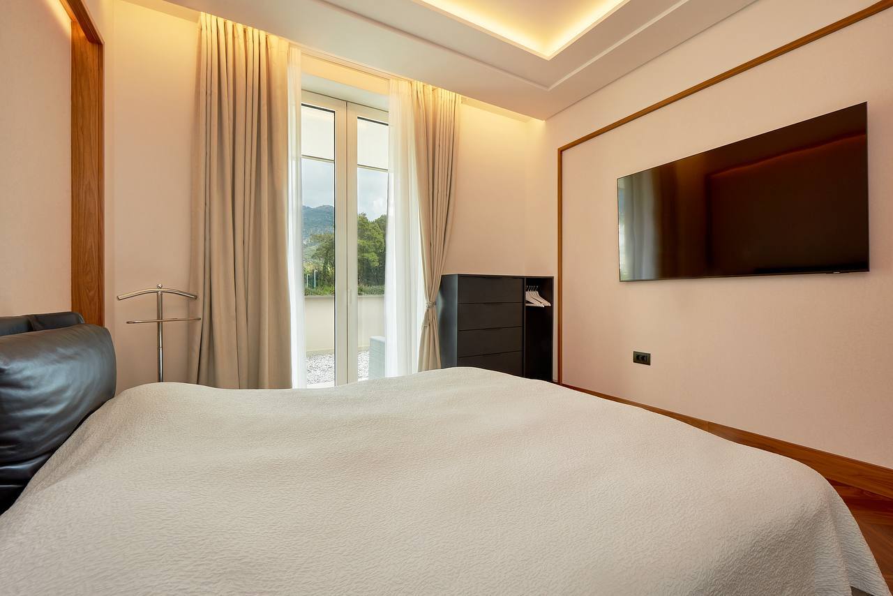 Modernes Schlafzimmer in einer Wohnung in Porto Montenegro, Tivat, Montenegro: Doppelbett, TV und Bergblick.