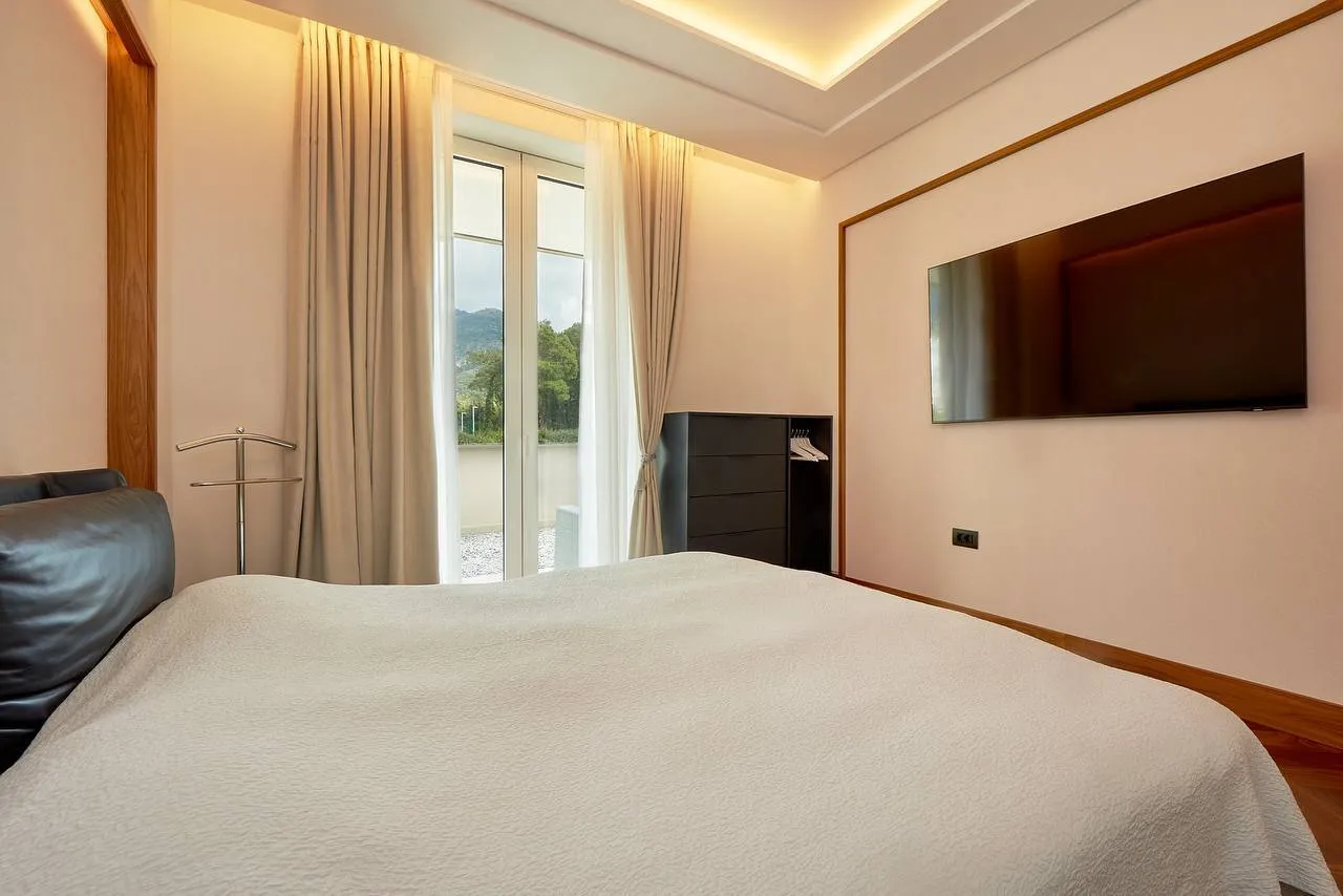 Moderne Schlafzimmer mit großem Bett, Wandfernseher und Balkon mit Bergblick.
