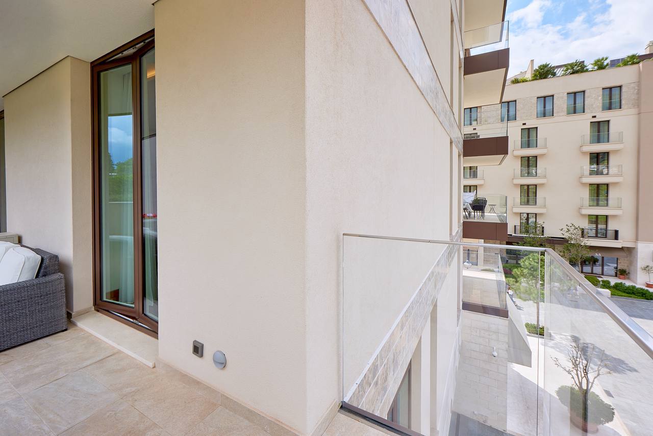 Balkon einer modernen Wohnung in Porto Montenegro, Tivat, Montenegro, mit Panoramaverglasung und Blick auf die Anlage.