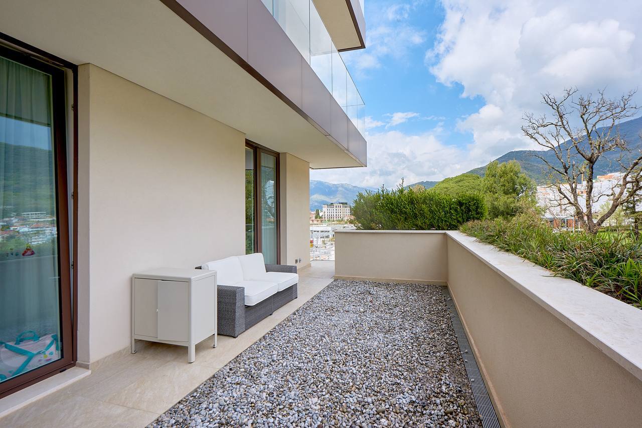 Geräumige Terrasse mit Möbeln in einer exklusiven Wohnung in Porto Montenegro, Tivat, Montenegro, mit Blick auf die Berge und die Stadt.