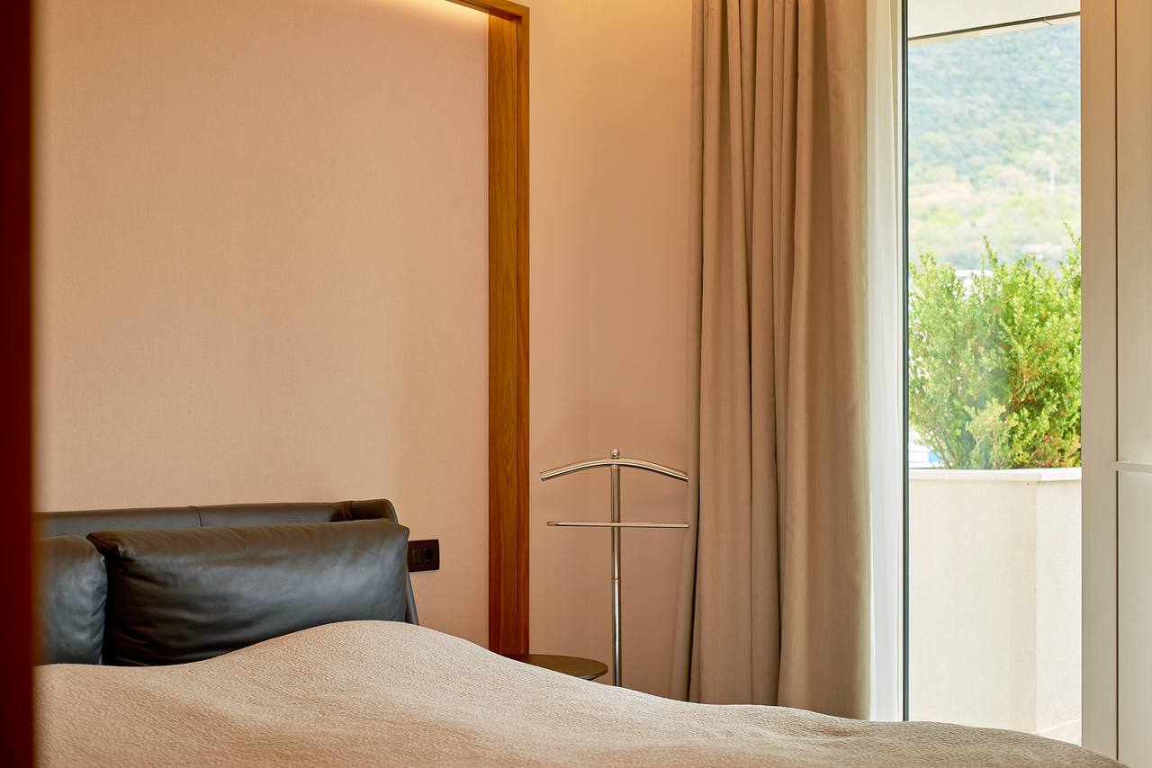 Modernes Schlafzimmer in einer Wohnung in Porto Montenegro, Tivat, Montenegro: Lederbett, Blick ins Grüne und auf die Terrasse.
