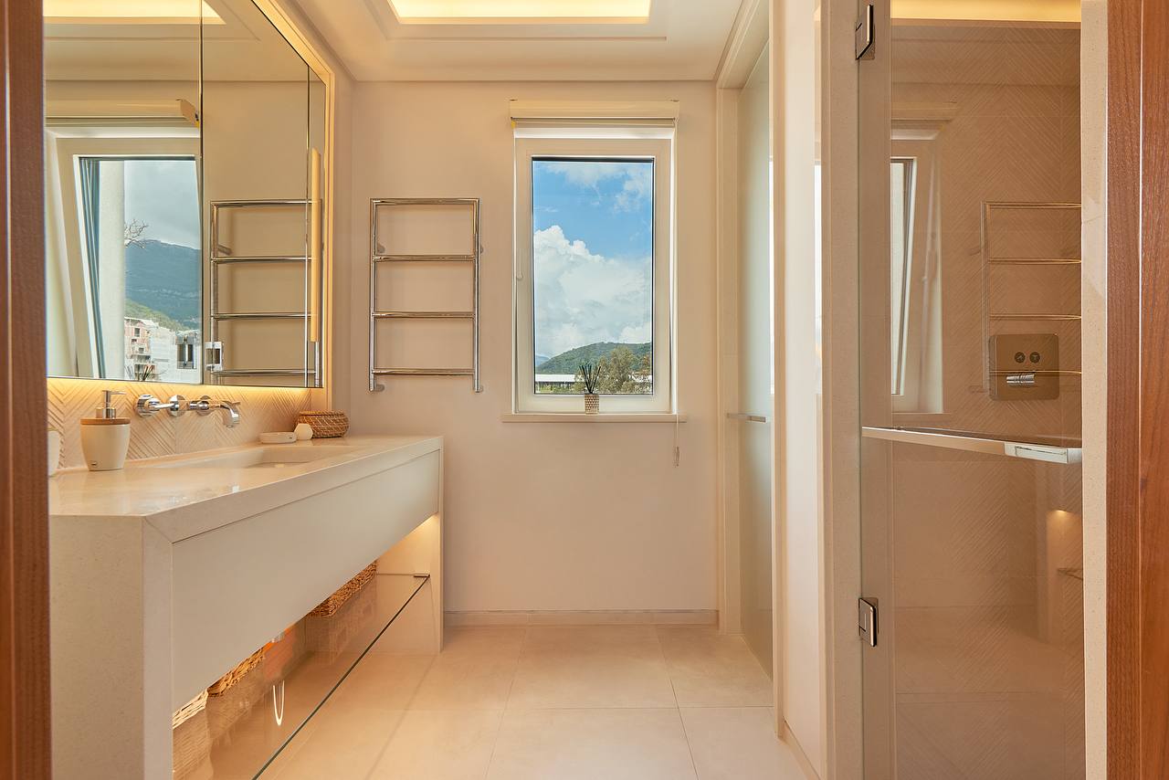 Modernes Badezimmer in einer Wohnung in Porto Montenegro, Tivat, Montenegro: helle Ausstattung, Dusche und Bergblick.