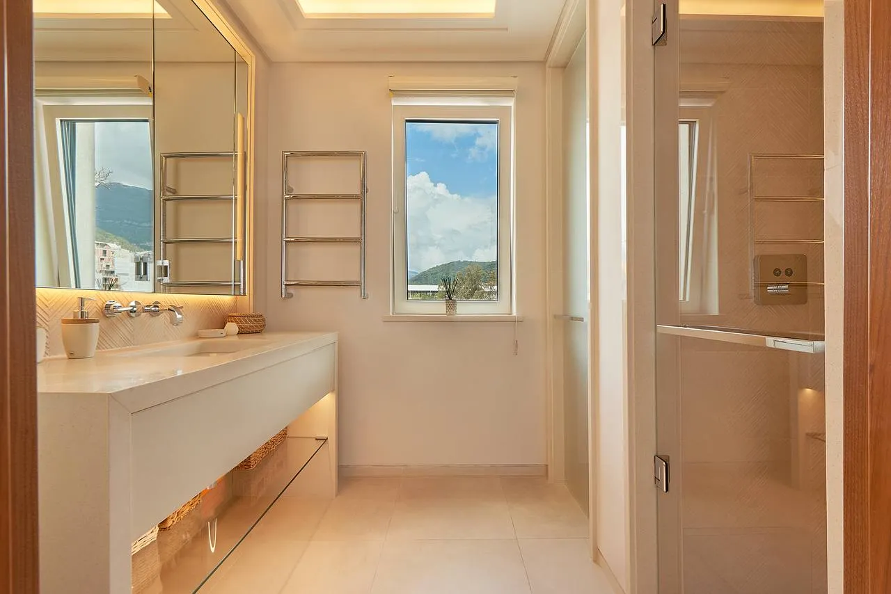 Moderne Badezimmer mit weißer Waschtischkonsole, großem Spiegel, beheiztem Handtuchhalter und Glasdusche.