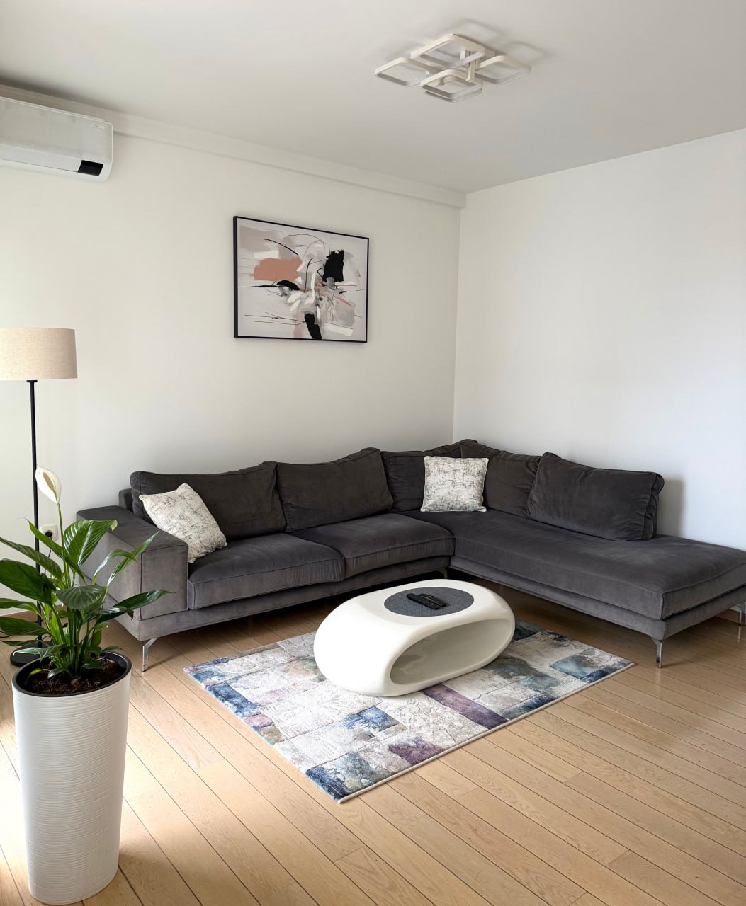 Salon moderne avec un canapé d'angle gris et une table basse blanche dans un appartement, Podgorica, Monténégro.