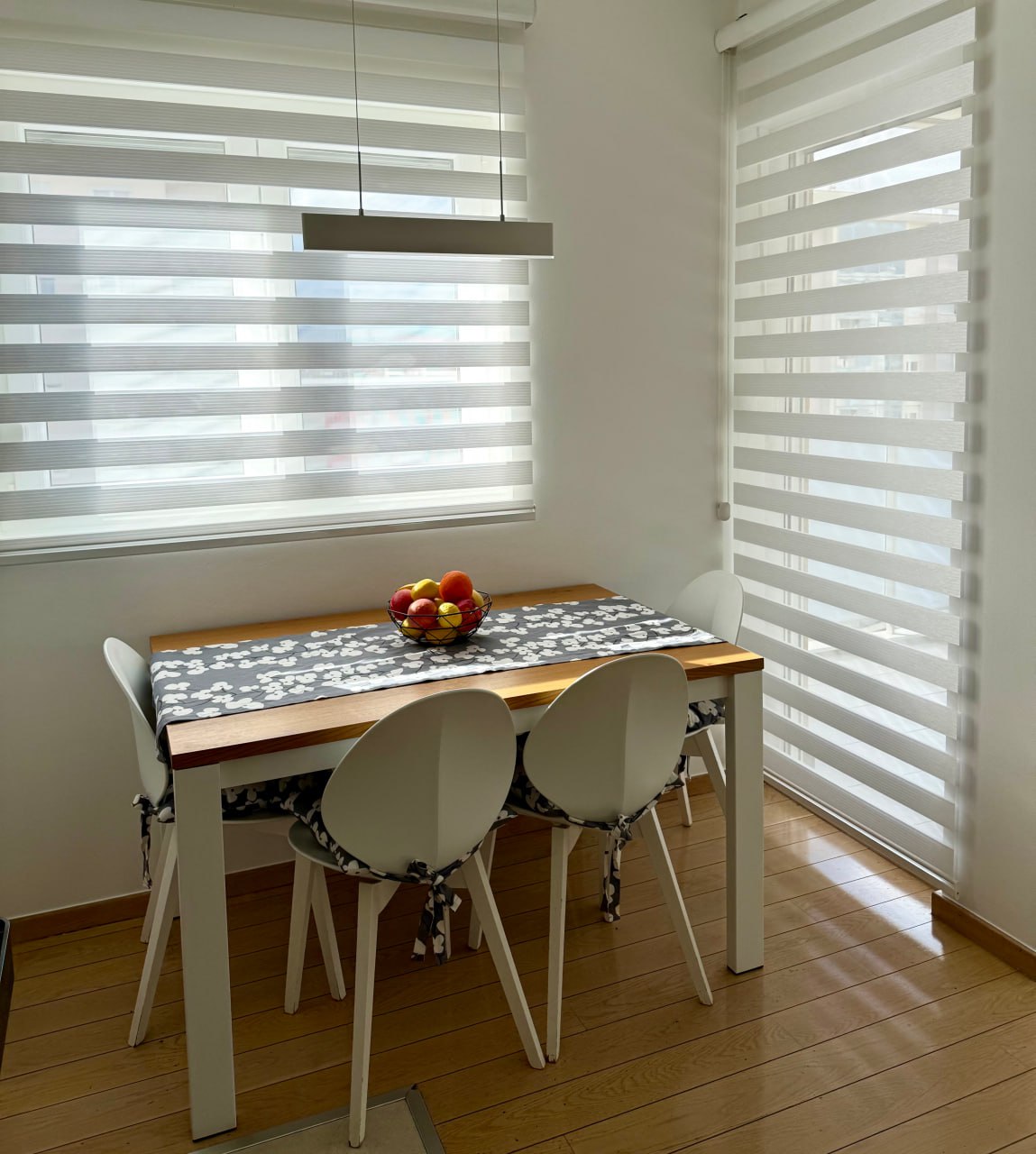 Zone repas avec une table en bois et des chaises blanches dans un appartement moderne, Podgorica, Monténégro.