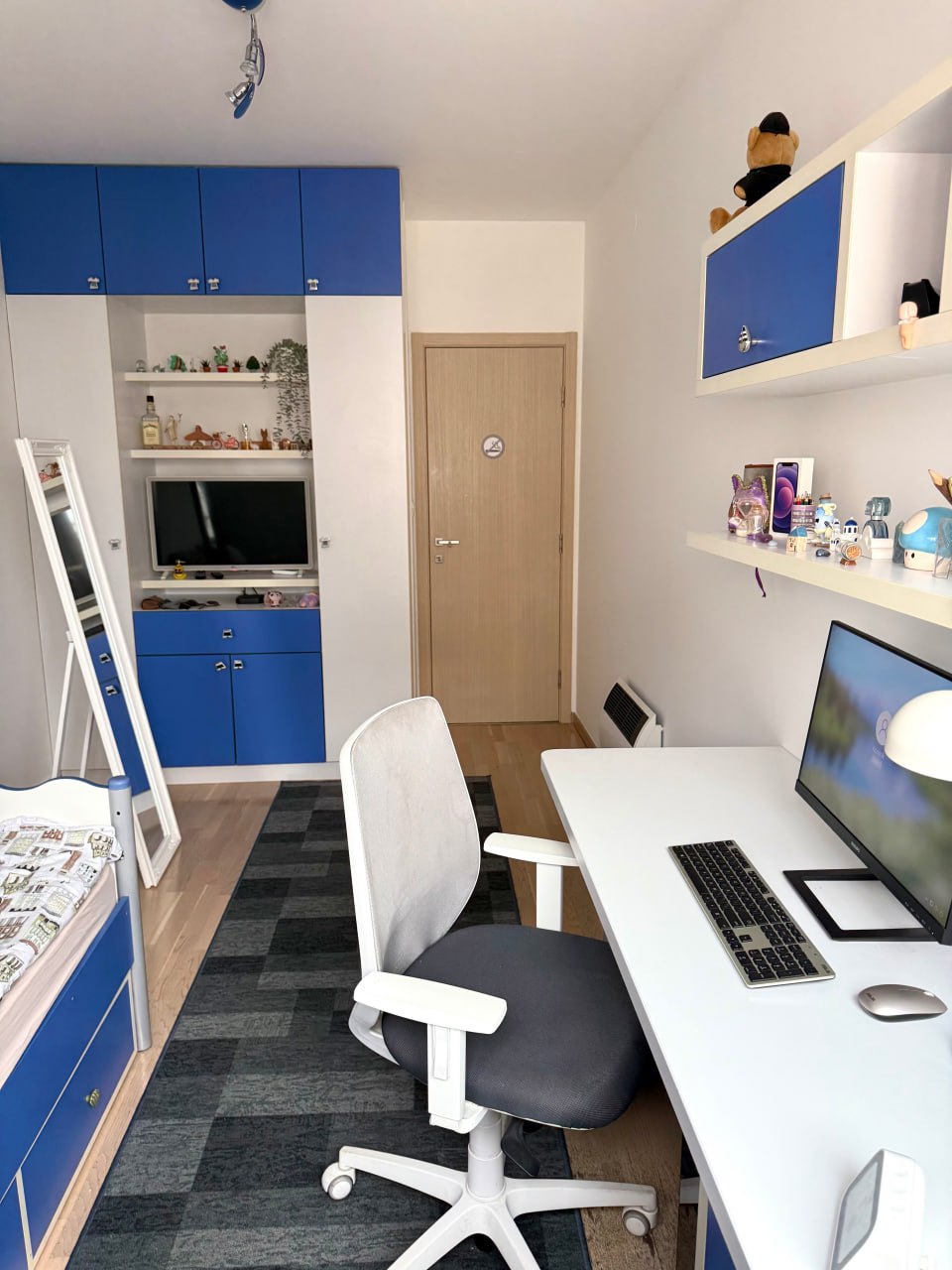 Chambre d'enfant avec espace de travail et mobilier bleu dans un appartement à Podgorica, Monténégro. Intérieur moderne avec un PC.