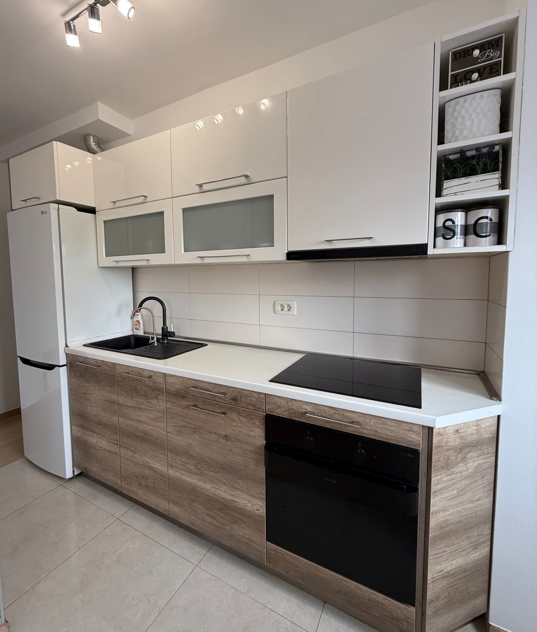 Cuisine moderne dans un appartement à Podgorica, Monténégro : meubles blancs, façades en bois, électroménager encastré et carrelage.