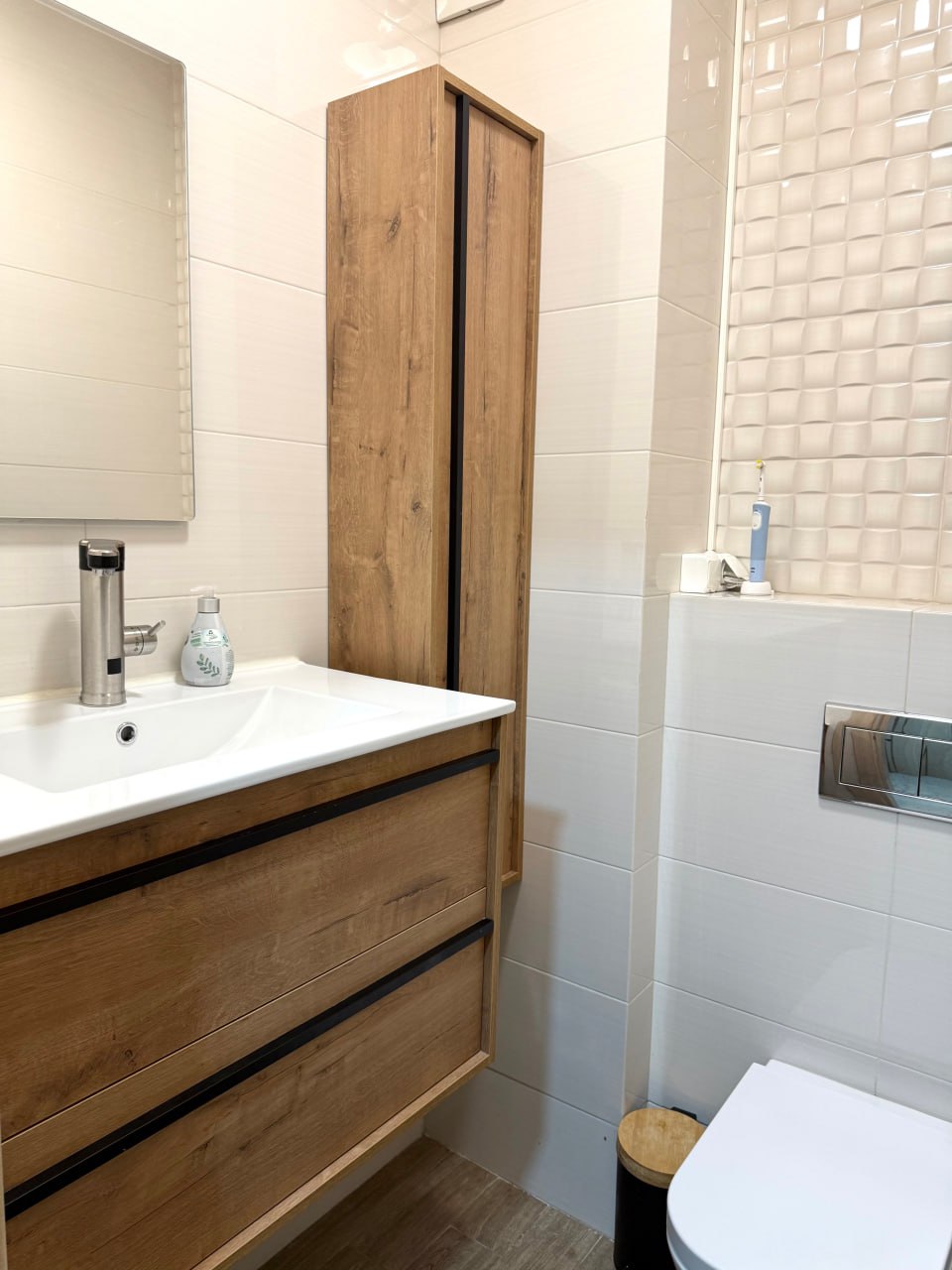 Salle de bain moderne dans un appartement, Podgorica, Monténégro : carrelage clair, mobilier en bois, sanitaires suspendus.