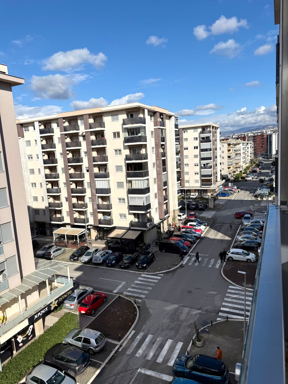 Vue depuis la fenêtre d'un appartement à Podgorica, Monténégro : développement urbain, quartier résidentiel et parking près de l'immeuble par une journée ensoleillée.