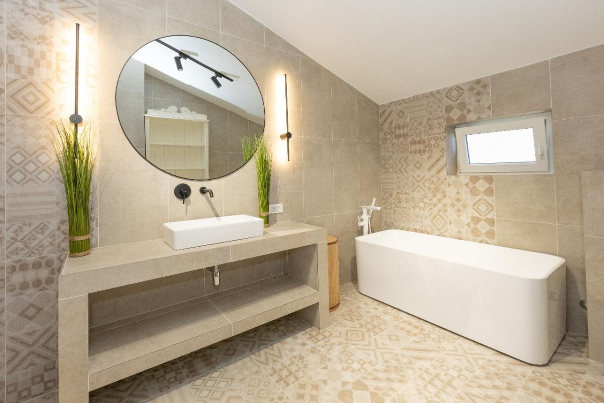 Salle de bains moderne avec baignoire blanche et plan de travail en pierre dans une maison à Tivat, Monténégro. Carrelage à motif.