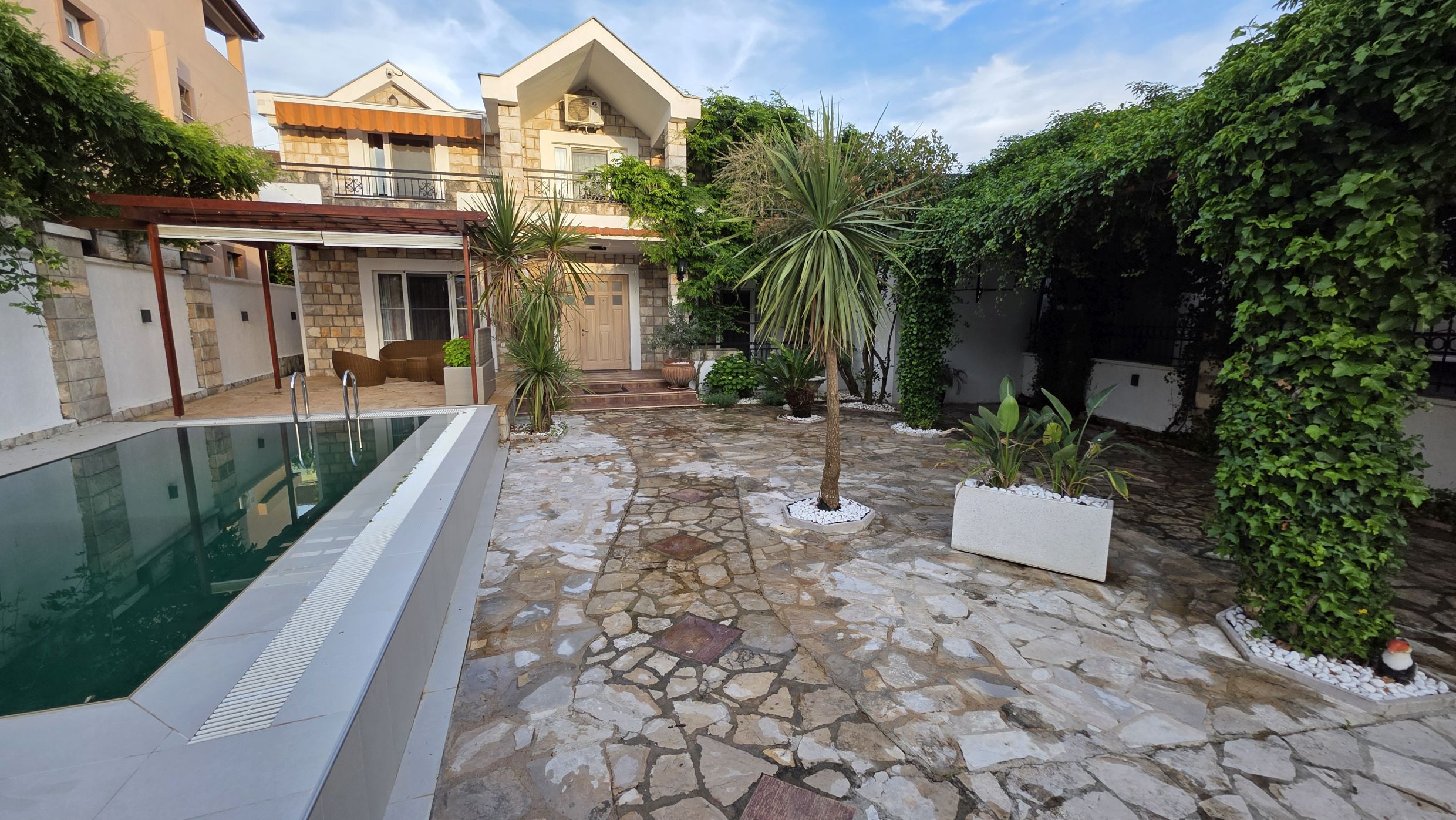 Villa de deux étages avec piscine et jardin verdoyant à Tivat, Monténégro : façade en pierre et terrasse accueillante.