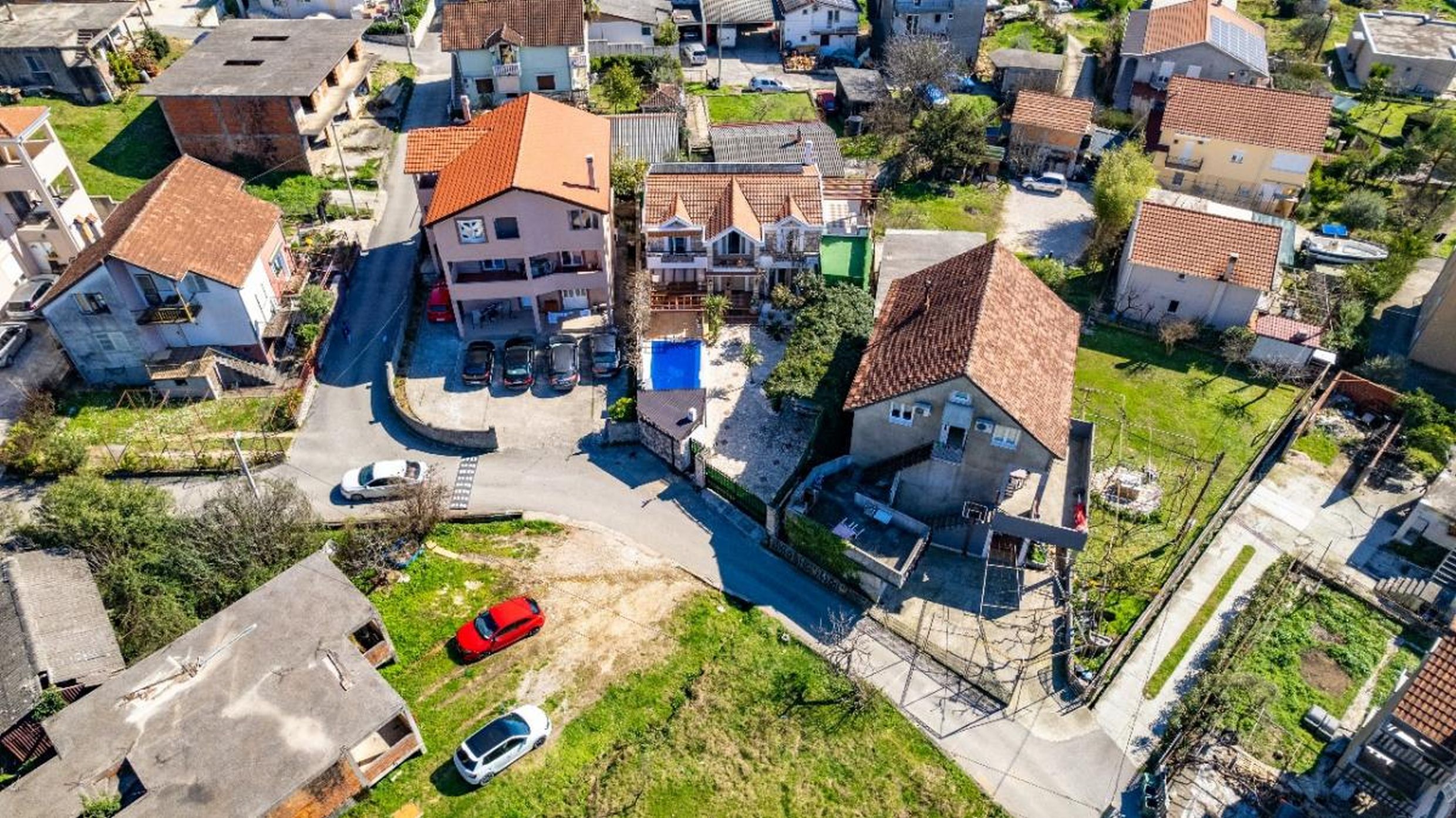 Vue aérienne de maisons privées aux toits en tuiles et avec piscine à Tivat, Monténégro, quartier avec parking.
