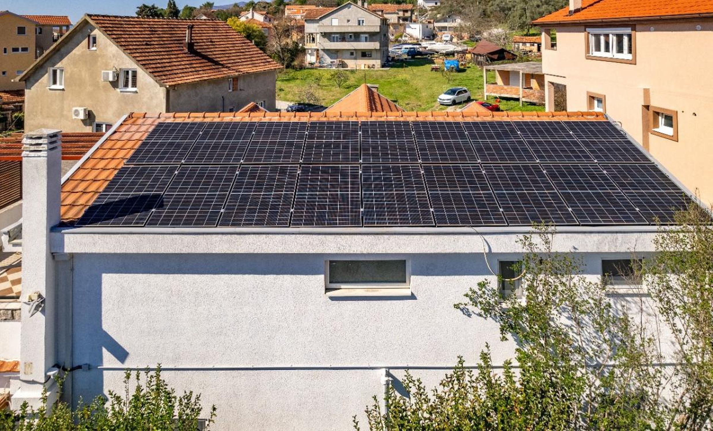 Panneaux solaires modernes sur le toit d’une maison individuelle à Tivat, Monténégro, vue sur un quartier résidentiel aux toits de tuiles.
