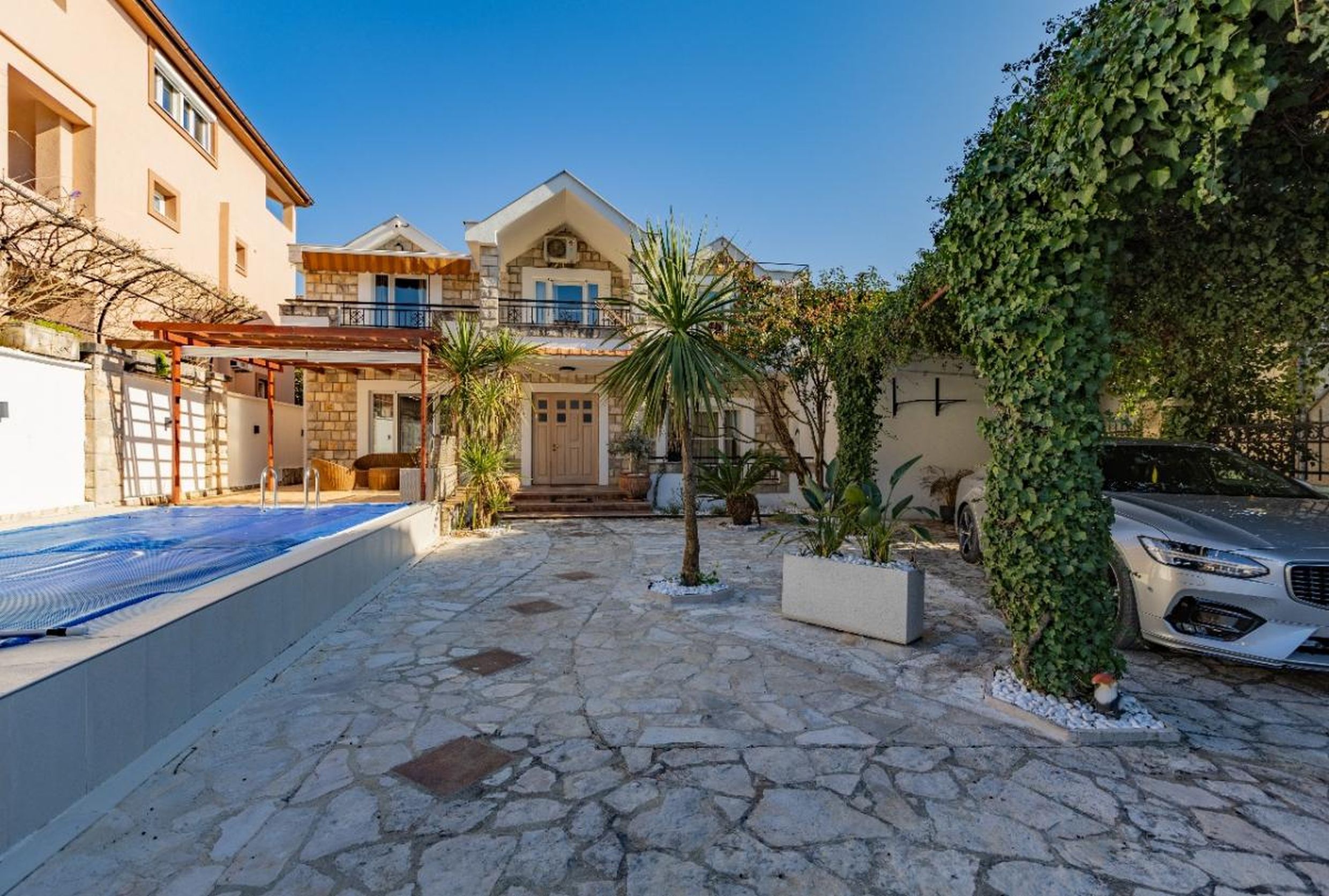 Villa de deux étages à Tivat, Monténégro : façade en pierre, piscine privée, terrasse et parking dans la cour.