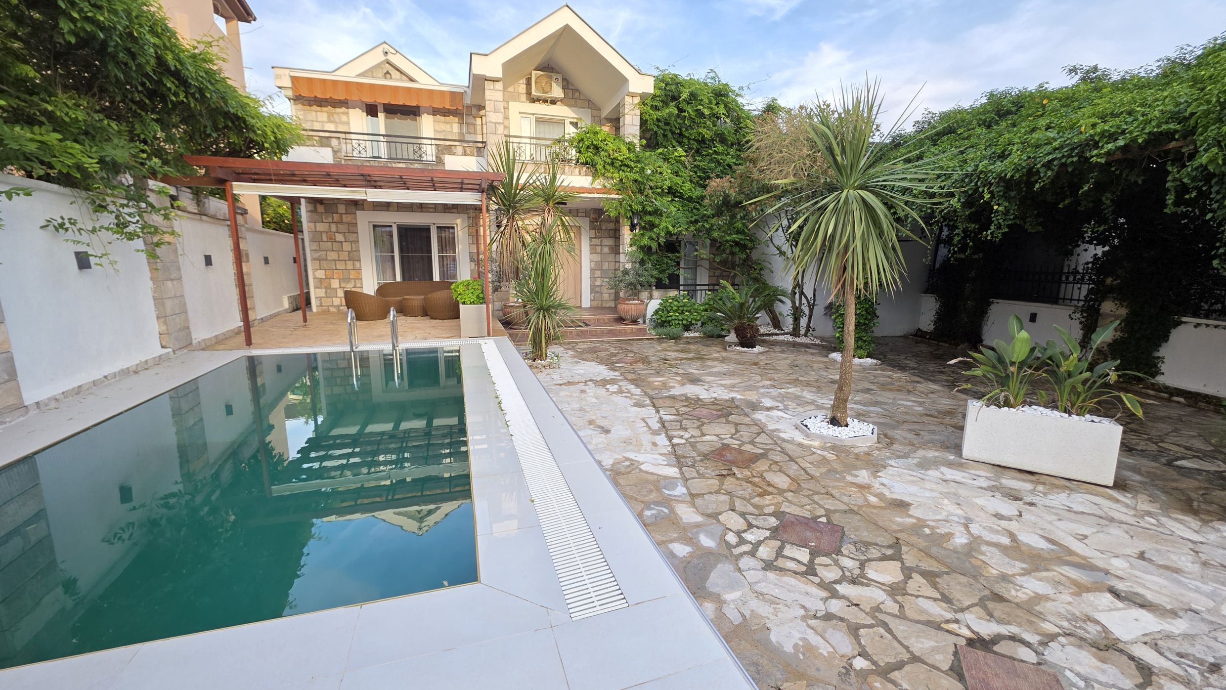 Villa à deux étages à Tivat, Monténégro : façade en pierre, piscine privée, terrasse meublée et jardin bien entretenu.