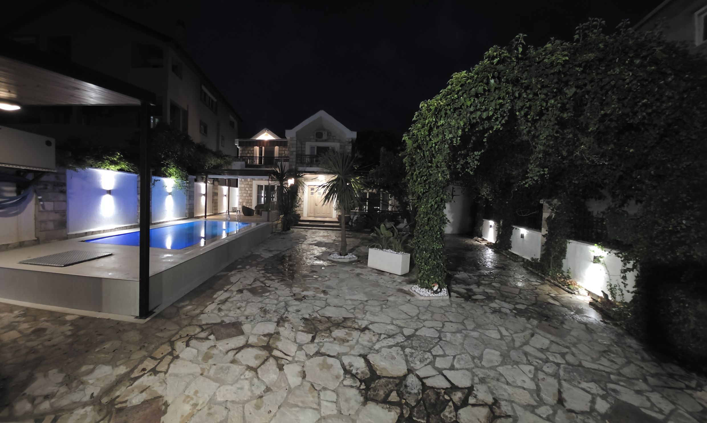 Maison à deux étages à Tivat, Monténégro, avec éclairage nocturne, piscine privée et cour aménagée en pierre.