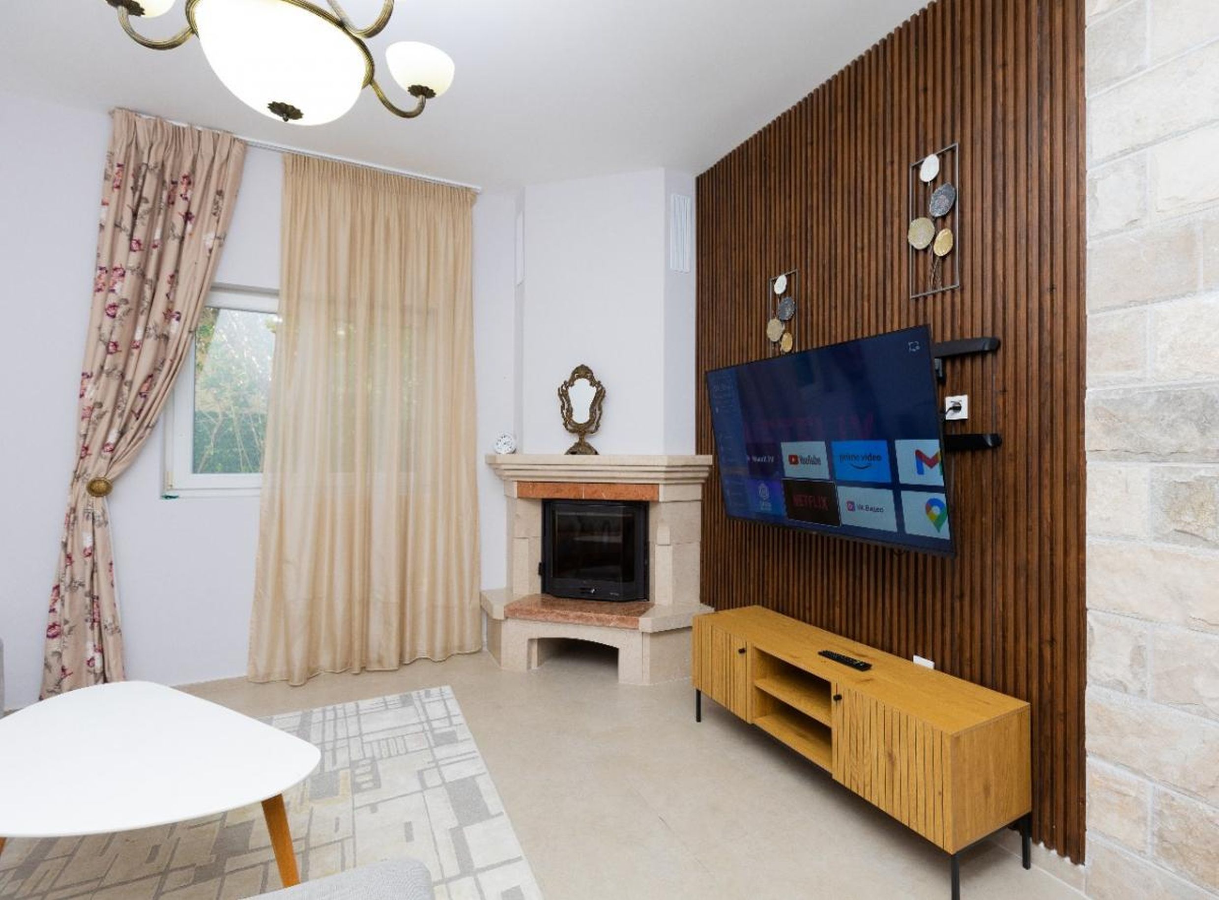 Salon dans une maison à Tivat, Monténégro : cheminée, coin TV avec lattes en bois, mobilier moderne et intérieur chaleureux.