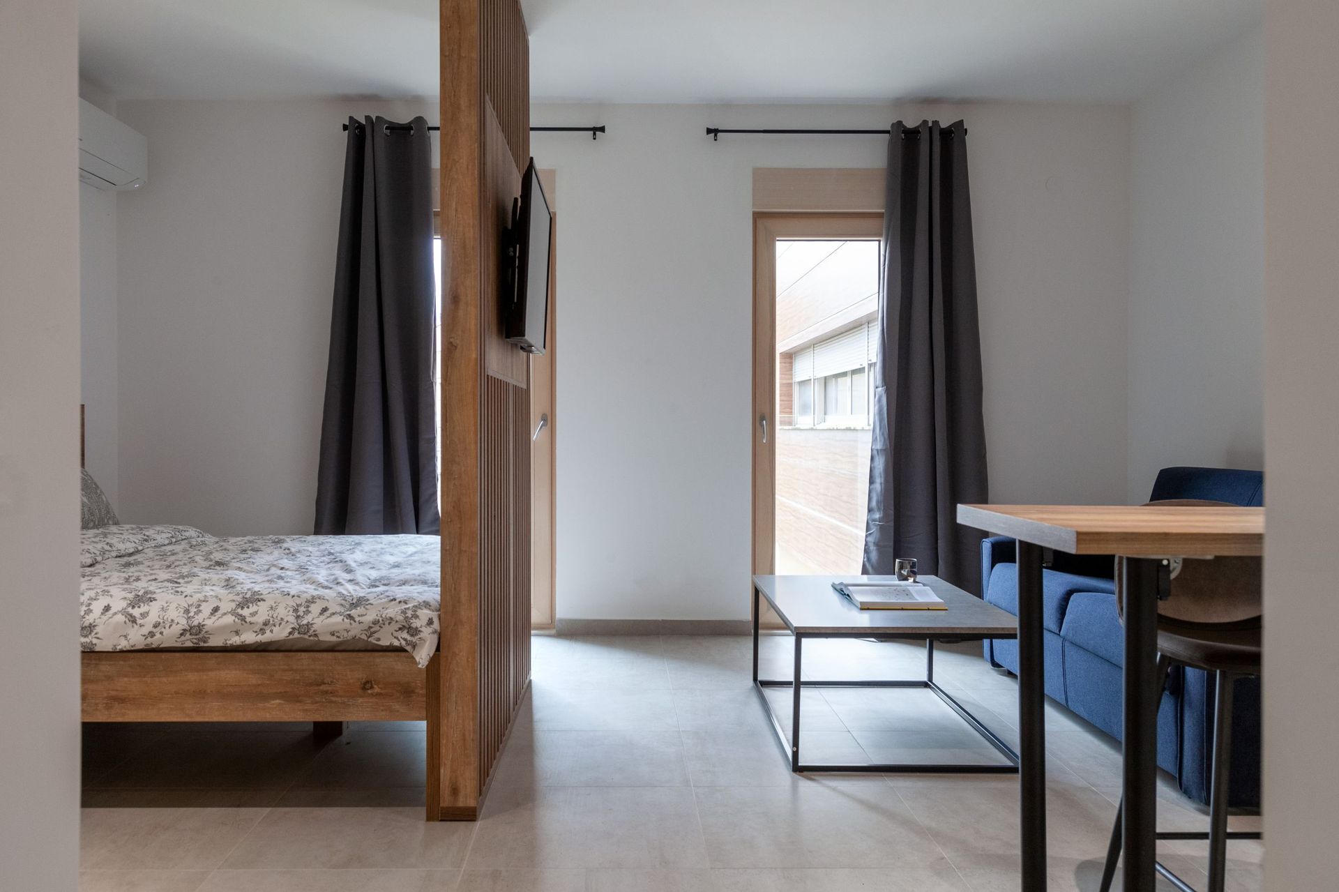 Modernes Wohnzimmer mit Bett und Sitzecke in einer Wohnung, Kotor, Montenegro: Holztrennwand und Zugang zum Balkon.