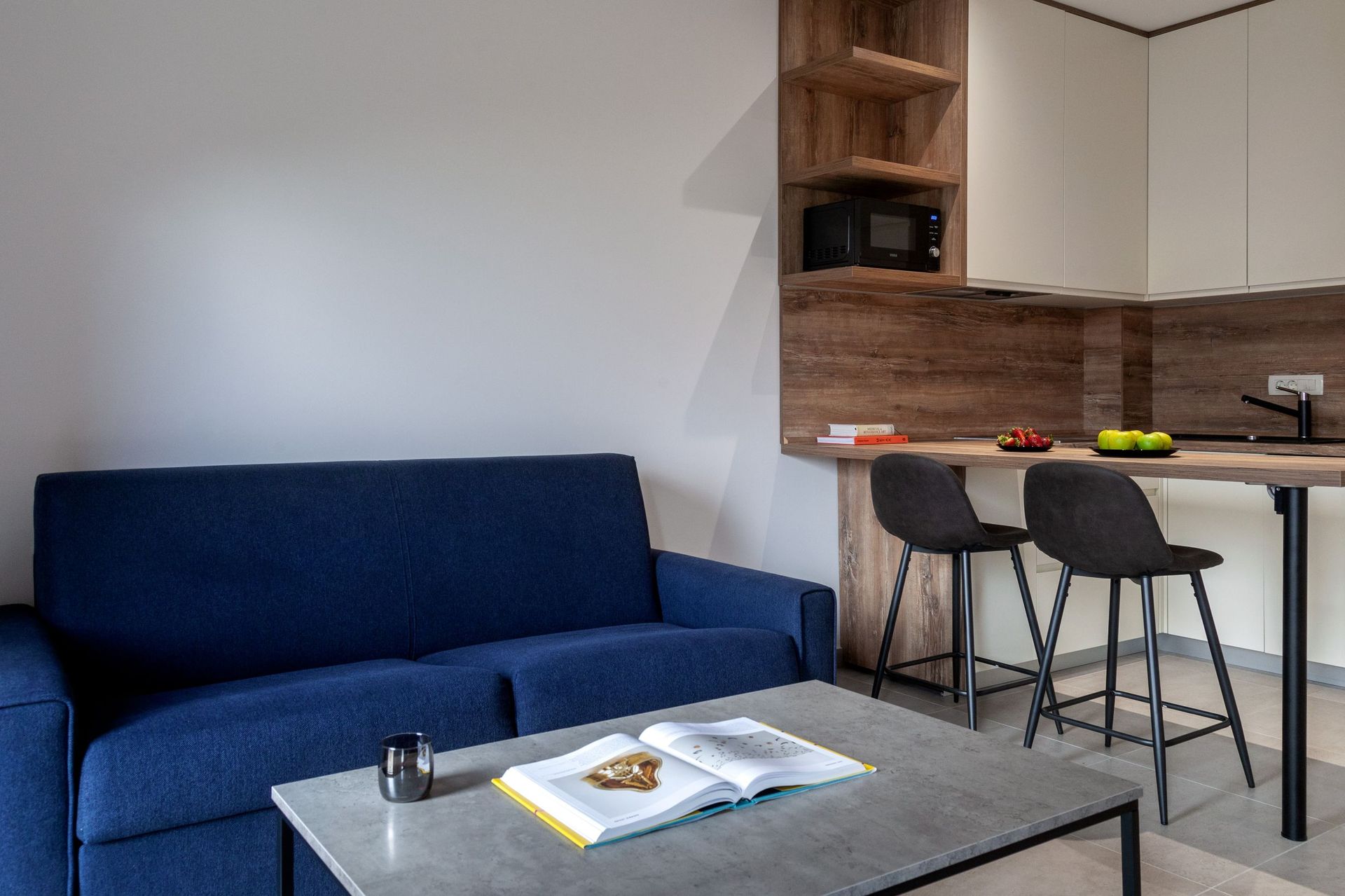 Modernes Wohnzimmer mit blauem Sofa und Küchenbereich in einer Wohnung in Kotor, Montenegro: stilvolles Interieur und Bartheke