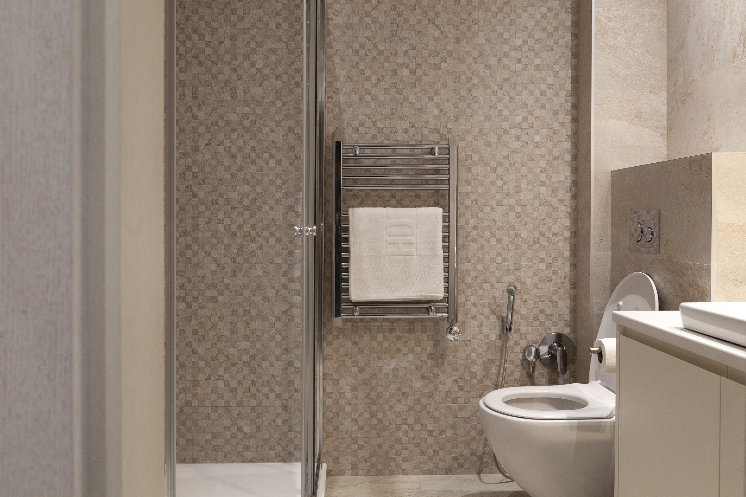 Modernes Badezimmer in einer Wohnung in Kotor, Montenegro: Duschkabine, wandhängendes WC und Handtuchheizkörper.