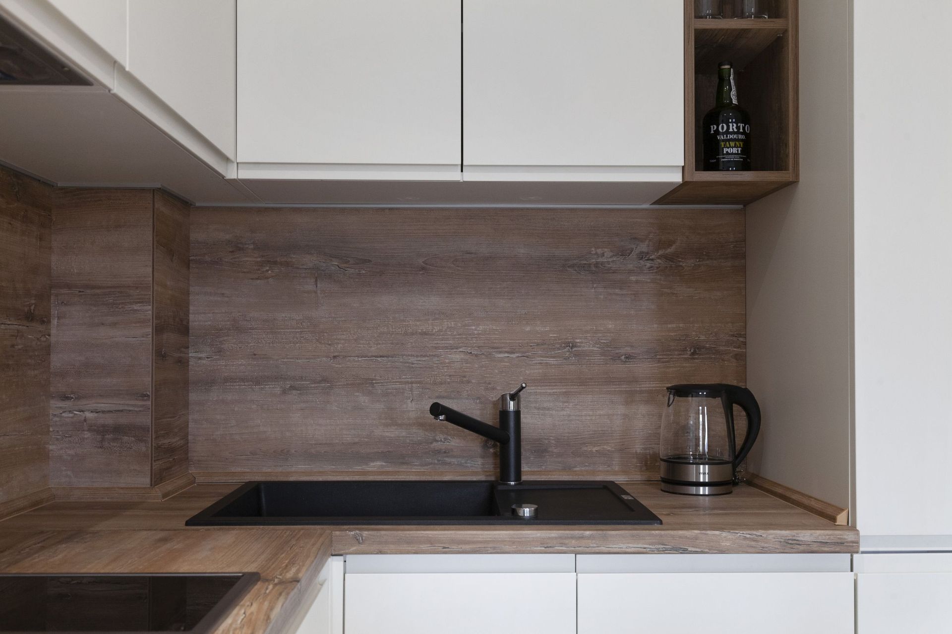 Moderne Küche mit weißen Fronten und Holzarbeitsplatte in einer Wohnung in Kotor, Montenegro: schwarze Spüle und Armatur.