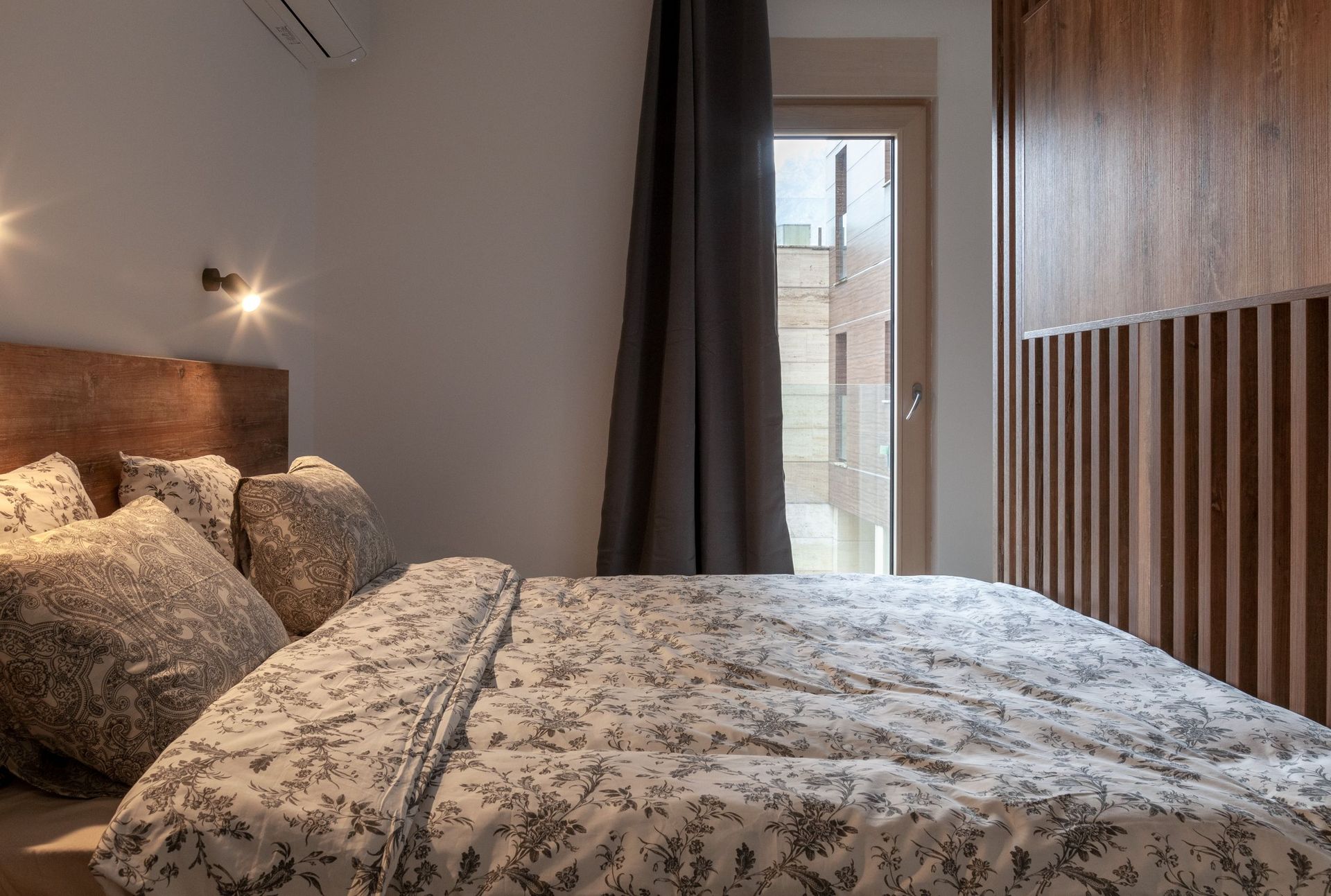 Modernes Schlafzimmer in einer Wohnung in Kotor, Montenegro: Doppelbett, Holzverkleidung an den Wänden und Zugang zum Balkon.