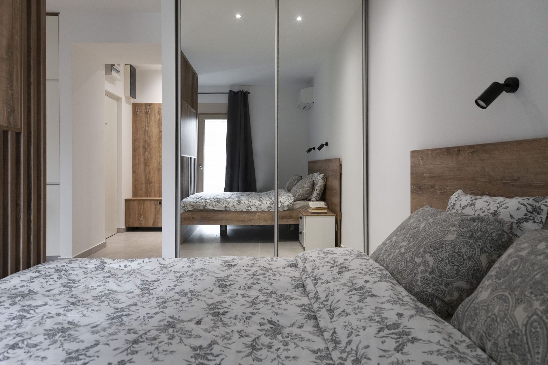 Modernes Schlafzimmer mit Doppelbett und Spiegelschiebetürenschrank in einer Wohnung, Stadt Kotor, Montenegro.