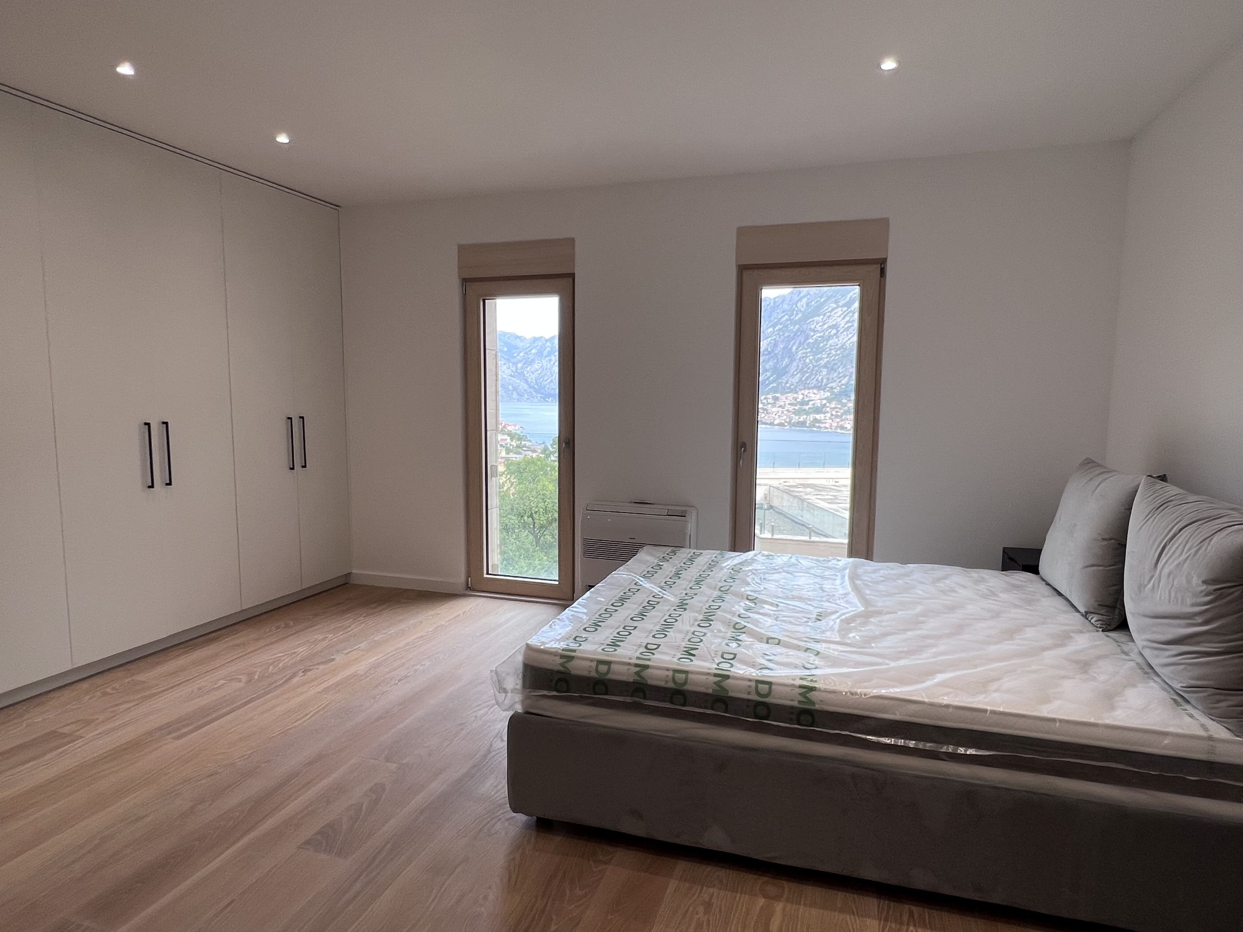 Schlafzimmer in einer neuen Wohnung in Kotor, Montenegro: Doppelbett, Einbauschrank und Blick auf die Bucht von Kotor.