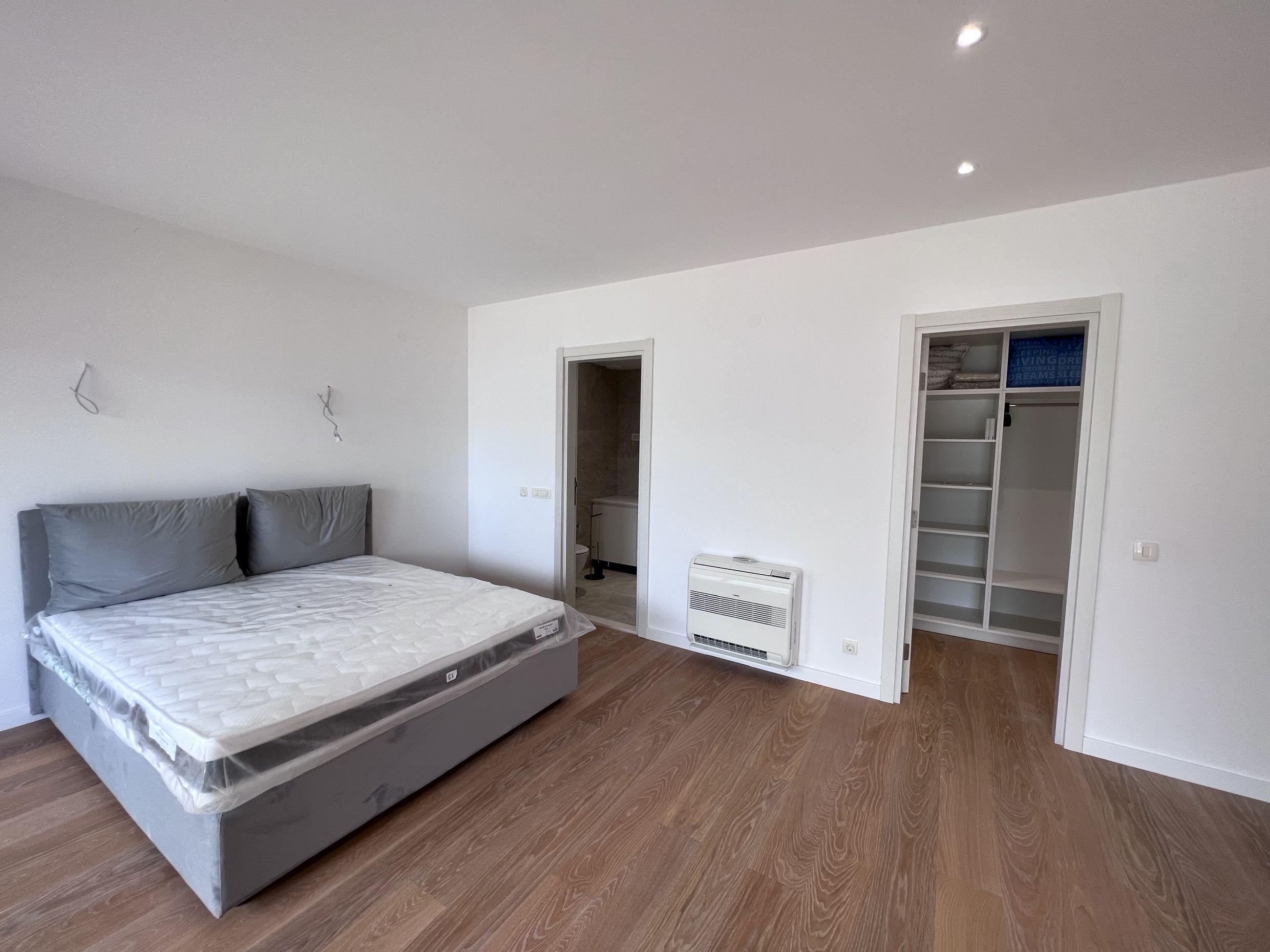 Helles Schlafzimmer in einer Wohnung in Kotor, Montenegro: Doppelbett, Einbauschrank, Parkett und separates Bad.
