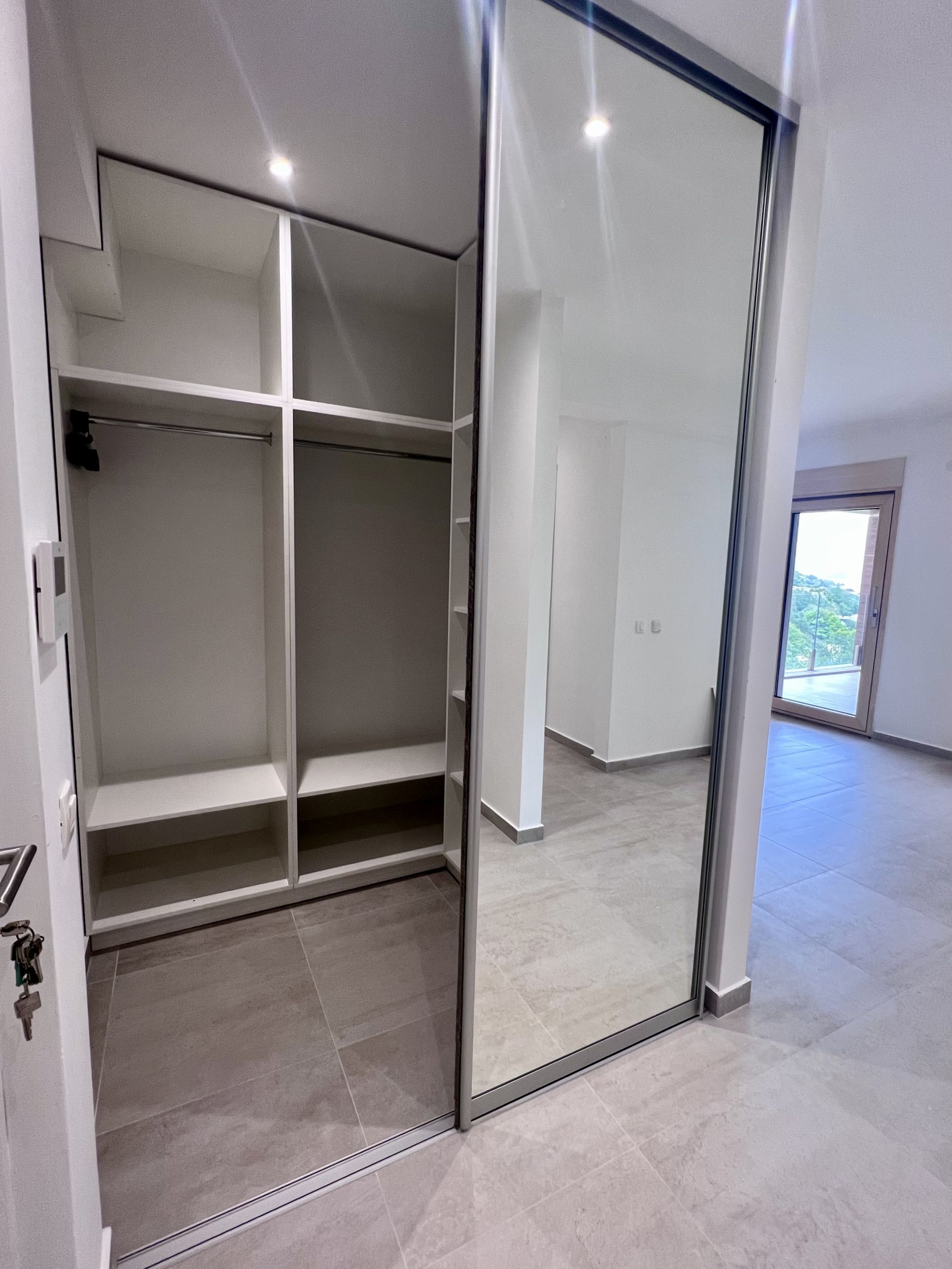 Einbauschrank mit Spiegeltüren in einem modernen Schlafzimmer einer Wohnung in Kotor, Montenegro, mit Bergblick.