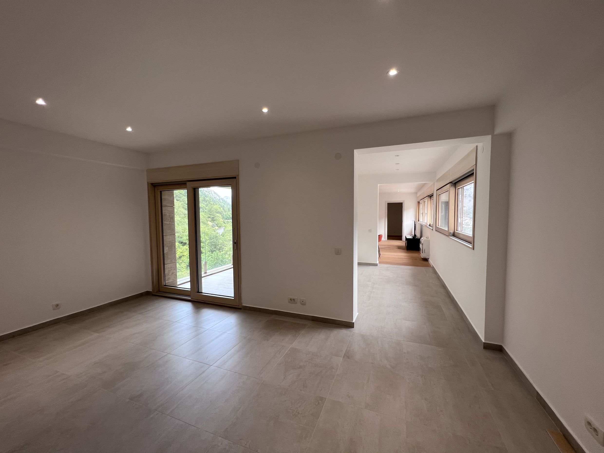 Helles Wohnzimmer mit Panoramablick auf die Berge in einer Wohnung, Kotor, Montenegro: moderne Ausstattung und Fliesenboden.