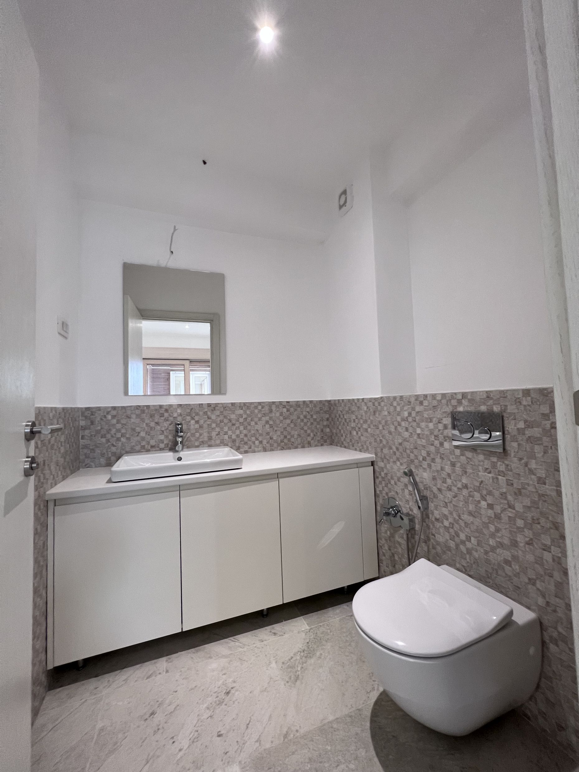 Modernes Badezimmer in einer Wohnung, Kotor, Montenegro: Hänge-WC, Waschtischunterschrank mit Waschbecken und Spiegel.