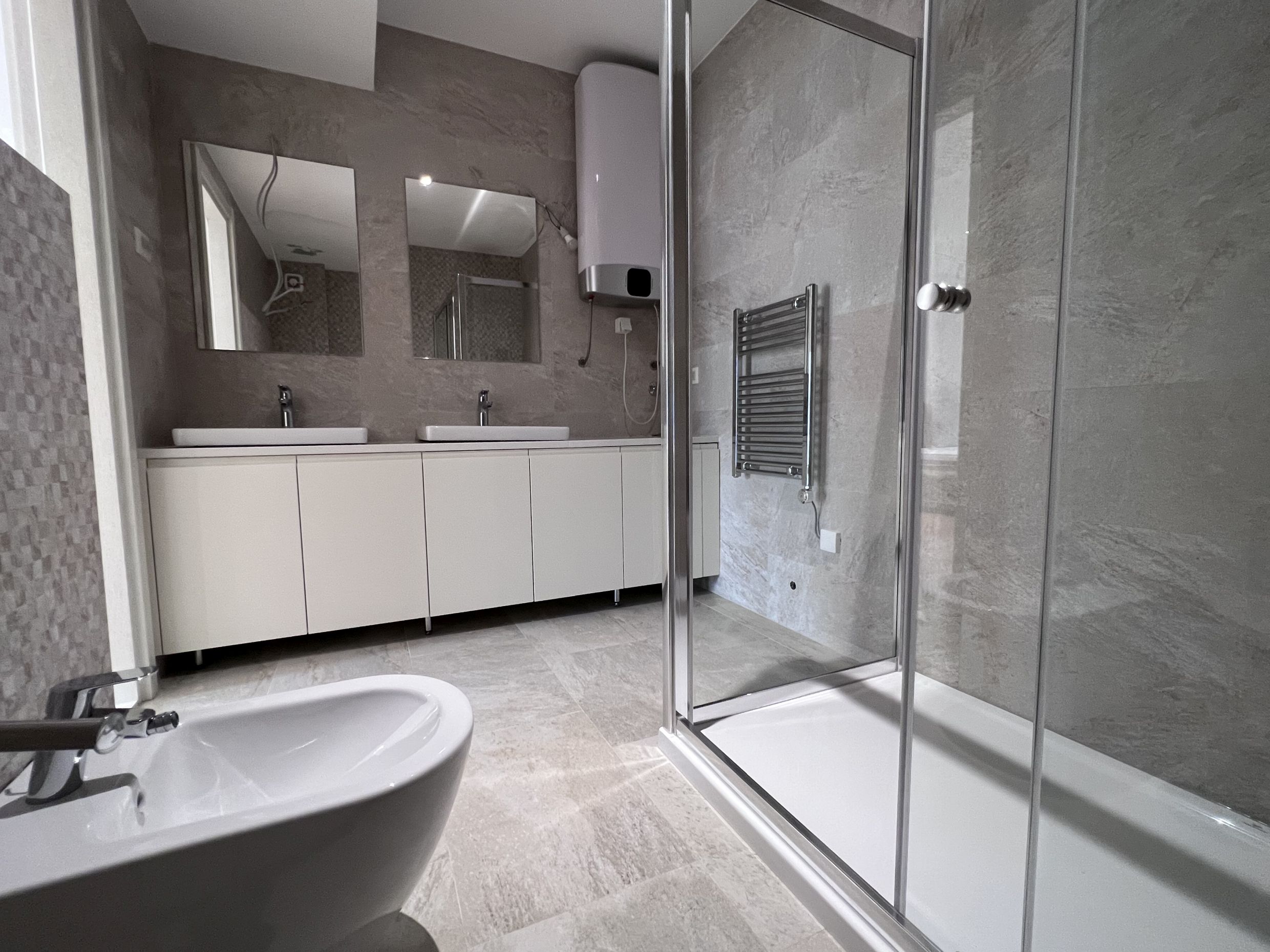 Modernes Badezimmer in einer Wohnung in Kotor, Montenegro: Duschkabine, Waschtisch mit zwei Waschbecken und Bidet.