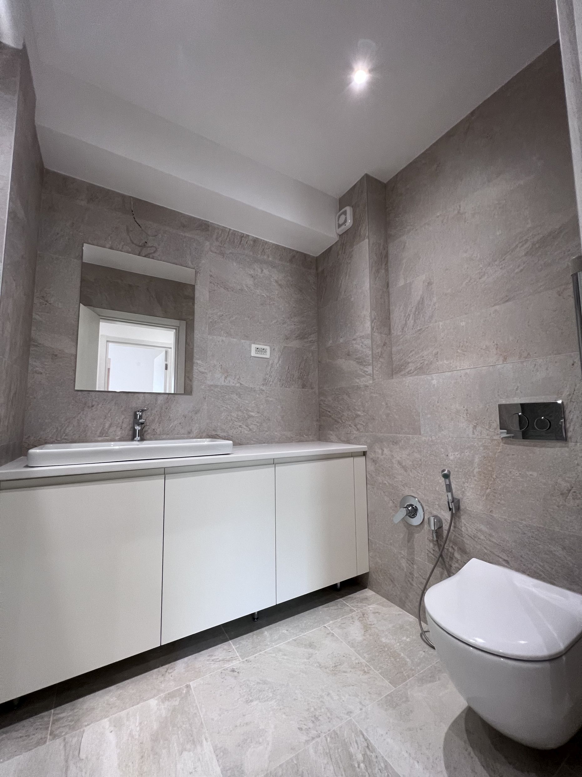 Modernes Badezimmer in einer Wohnung, Kotor, Montenegro: weiße Waschtischkonsole, Aufsatzwaschbecken und wandhängendes WC.